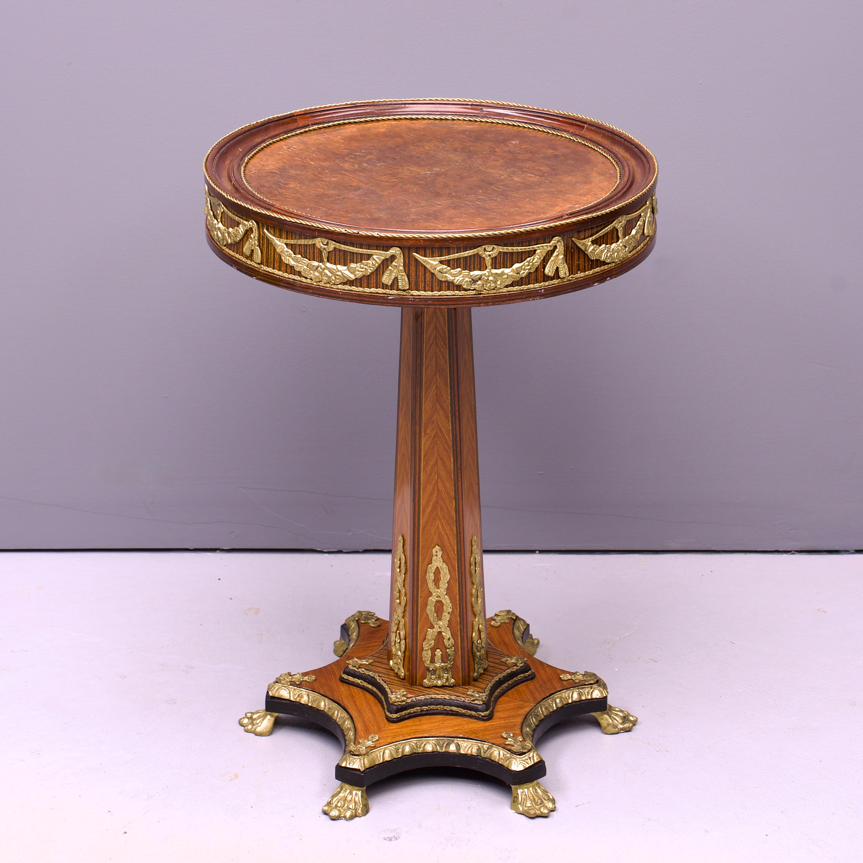 Fin du 19e siècle ou début du 20e siècle Table de centre circulaire en bronze doré, ronce de noyer et bois de rose. Il est doté d'un plateau à bords moulés et de guirlandes en laiton ou en bronze doré sur les côtés, et repose sur une tige hexagonale