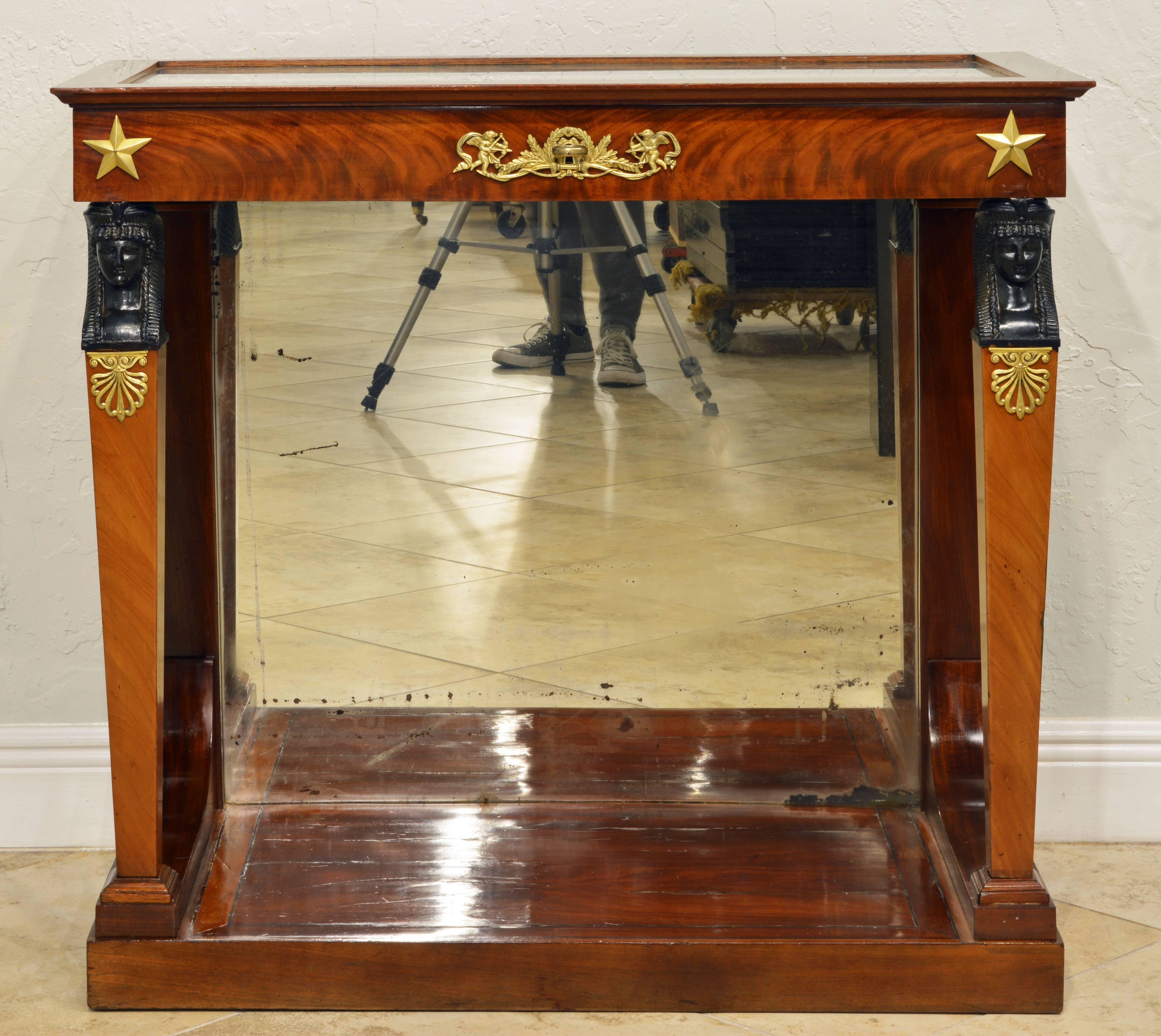 This rare and elegant vitrine console table features a wood framed glass top that opens up to a silk lined vitrine display compartment above a ormolu-mounted frieze resting on two square tapering front legs surmounted by carved ebonized Egyptian