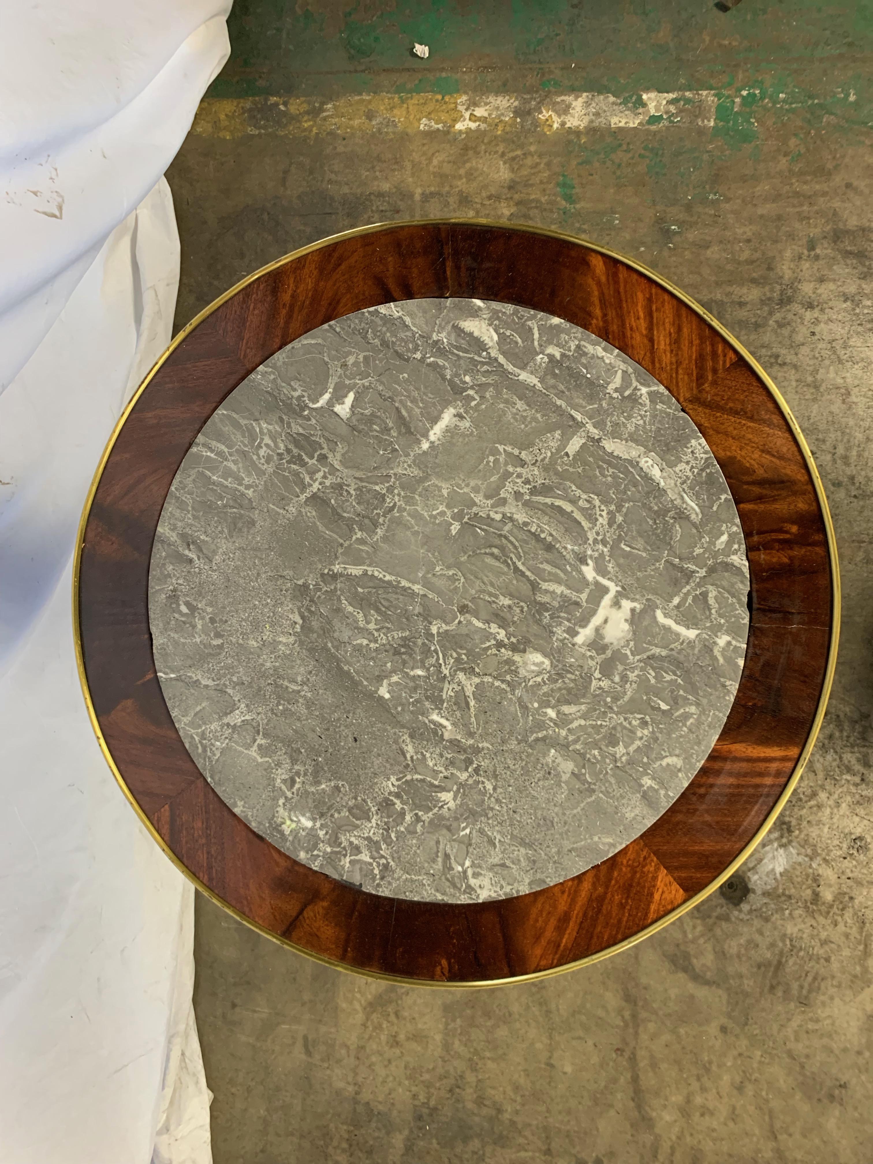 A French Empire style mahogany, giltwood and ebonized centre table, late 19th century. The circular top in set with St Anne marble. With swan neck supports and triform base.