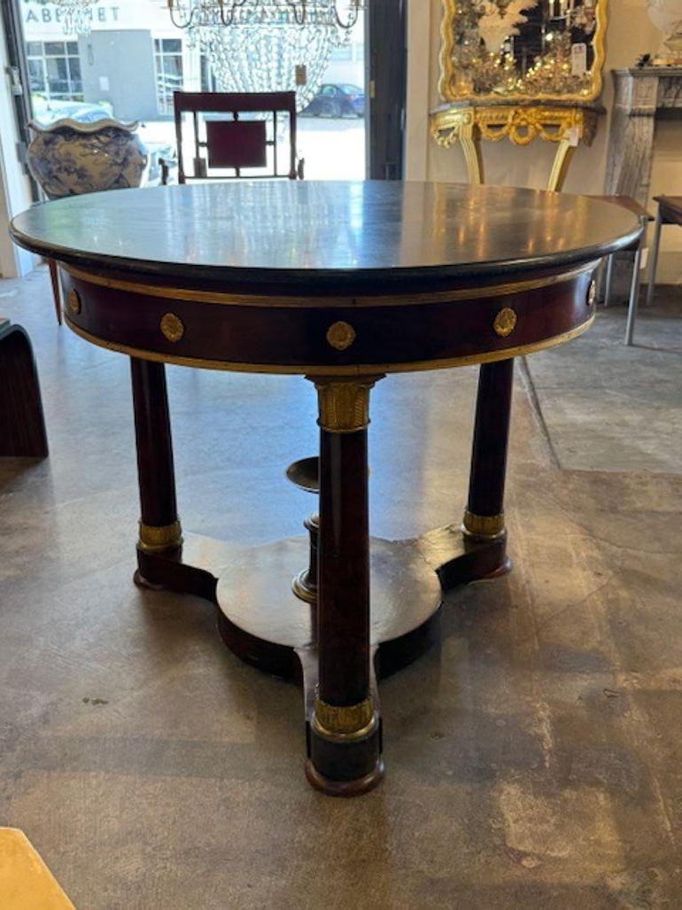Le produit est une superbe table en acajou de style Empire français du XIXe siècle, avec un plateau en marbre et des détails en laiton doré,  incarnant l'élégance et la sophistication. Il y a un magnifique  La finition du bois est  ajoute une touche