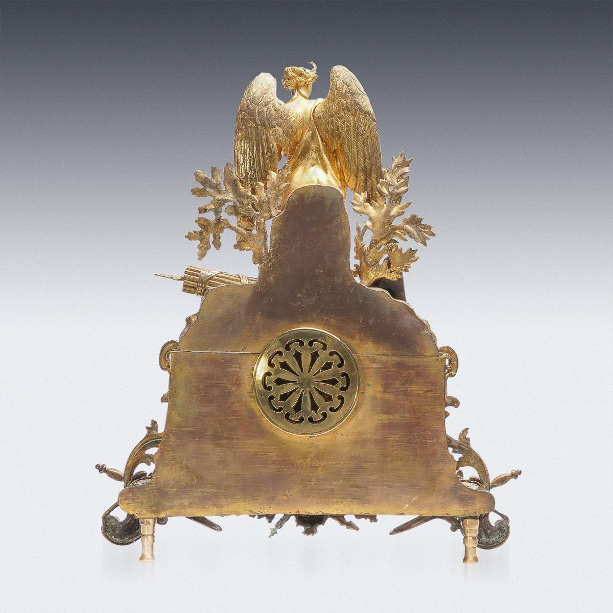 Antique 19th Century French Empire style ormolu bronze mantle clock. The foliate surround gilt dial, Inside with eight day movement with strike on bell. The top mounted with a figure of an angel on the rectangular base with applied reliefs, raised