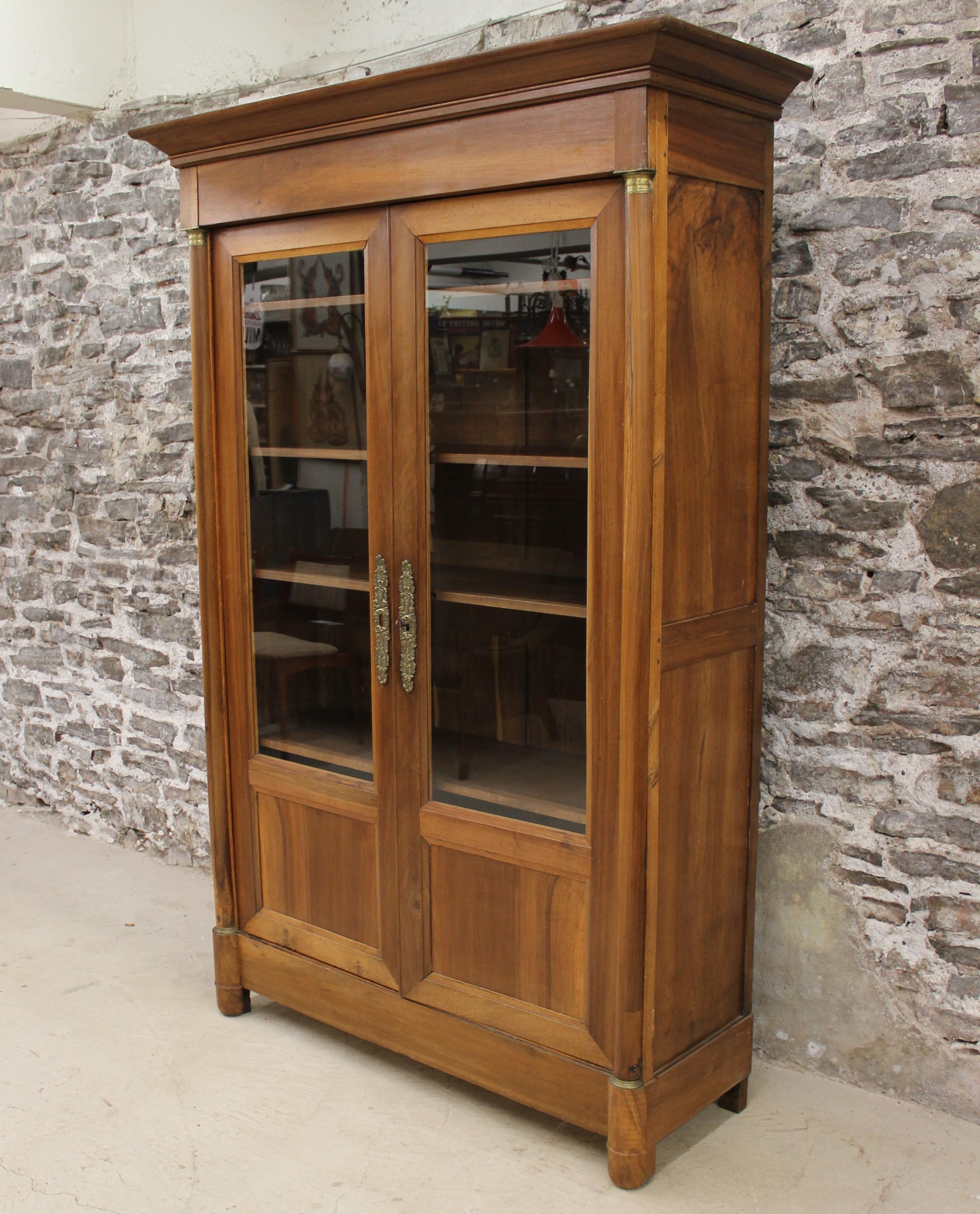 This 19th century French Empire style walnut cabinet features two-door, bronze accents and highlights and provides ample storage. This would be a perfect fit for either a kitchen or library.