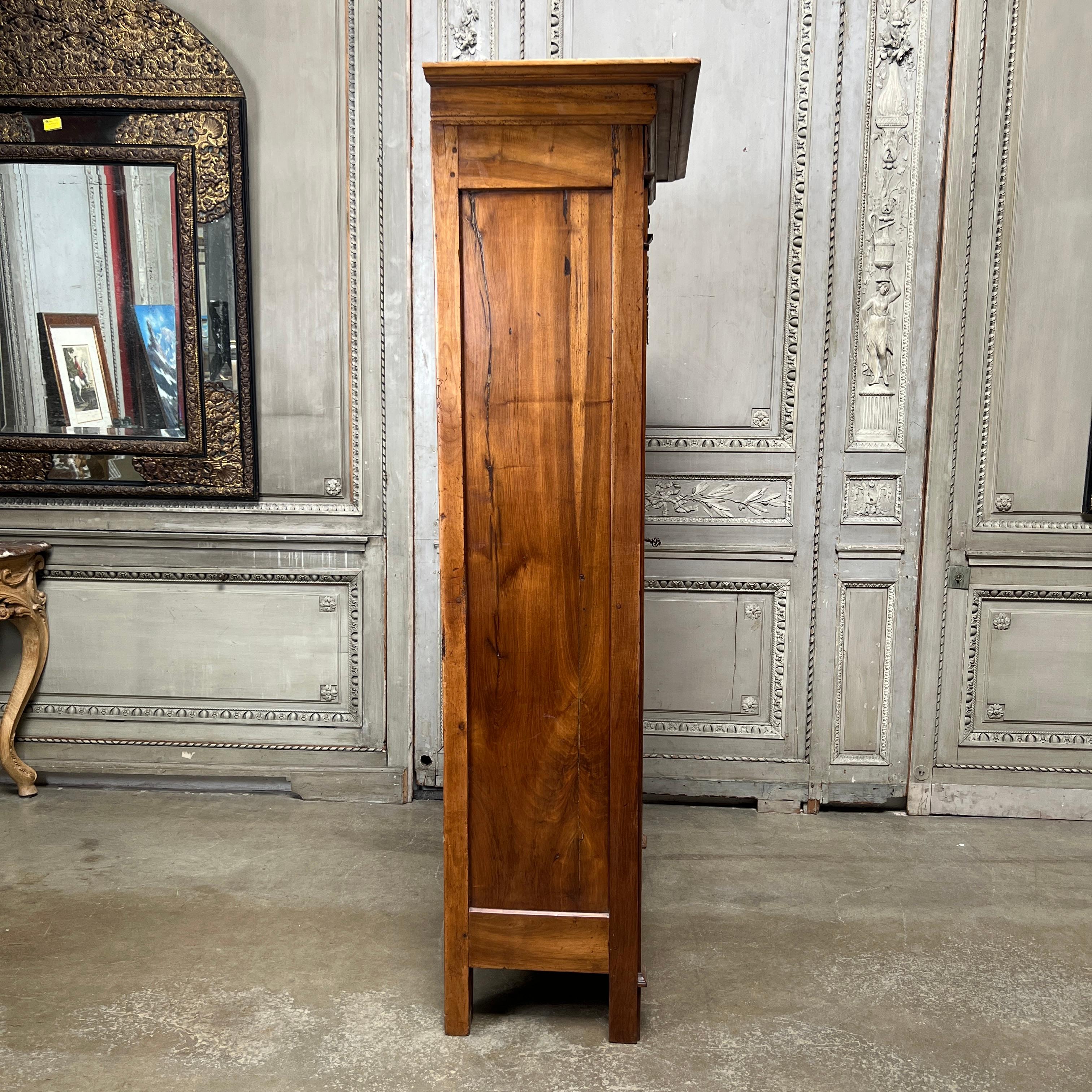 A small charming country French walnut Empire one door armoire-bookcase. 
This piece appears to be early 19th century and has nice neoclassical style bronze mounts. The glass may have been added at a later date by taking out a solid panel at the