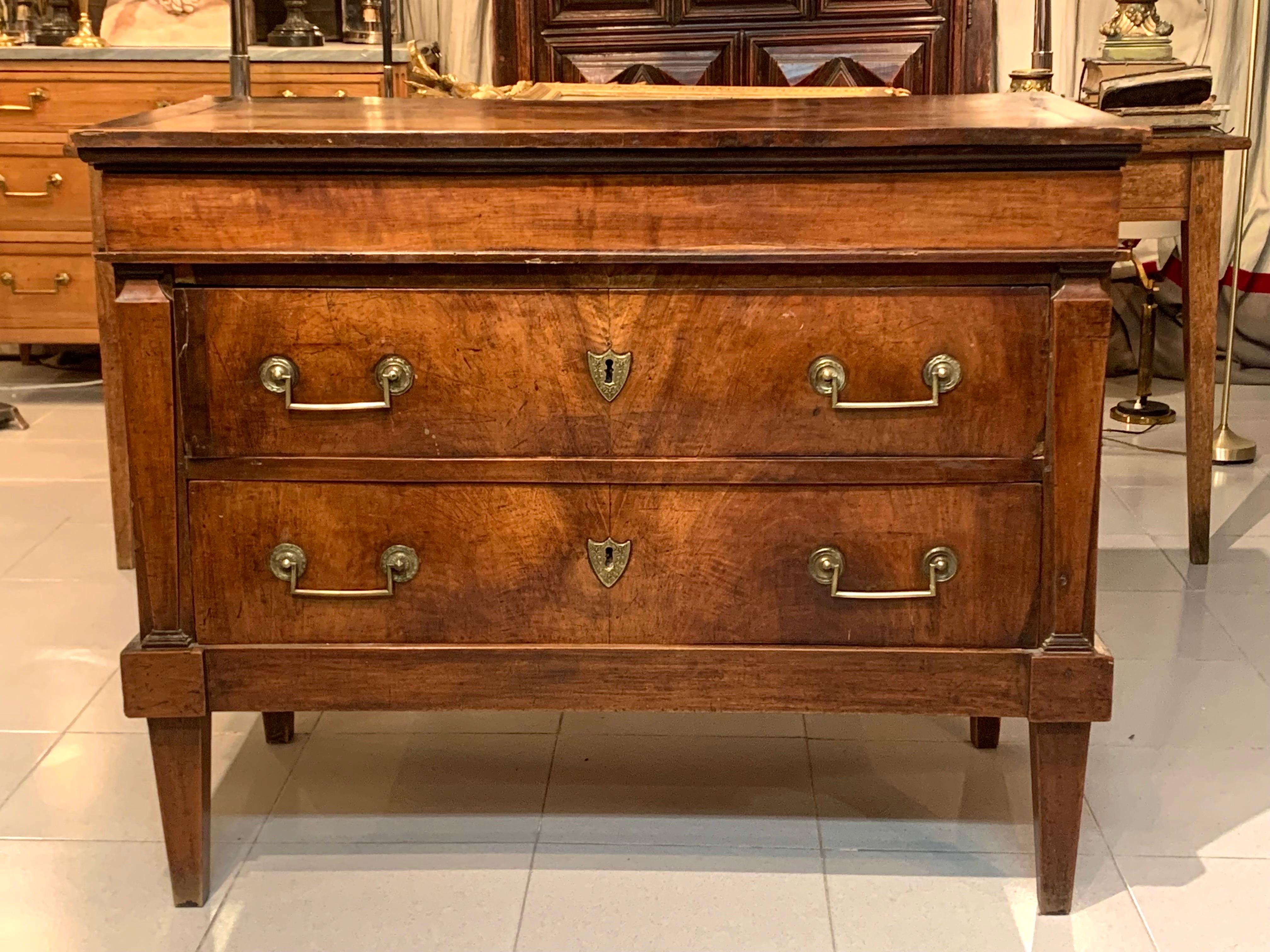 A rare French Empire period chest of drawers, in walnut wood with keyholes and gilded brass handles, the chest of drawers has two drawers and a top secret at the top, the sides are flanked by columns, the legs are stipite-shaped, the chest of