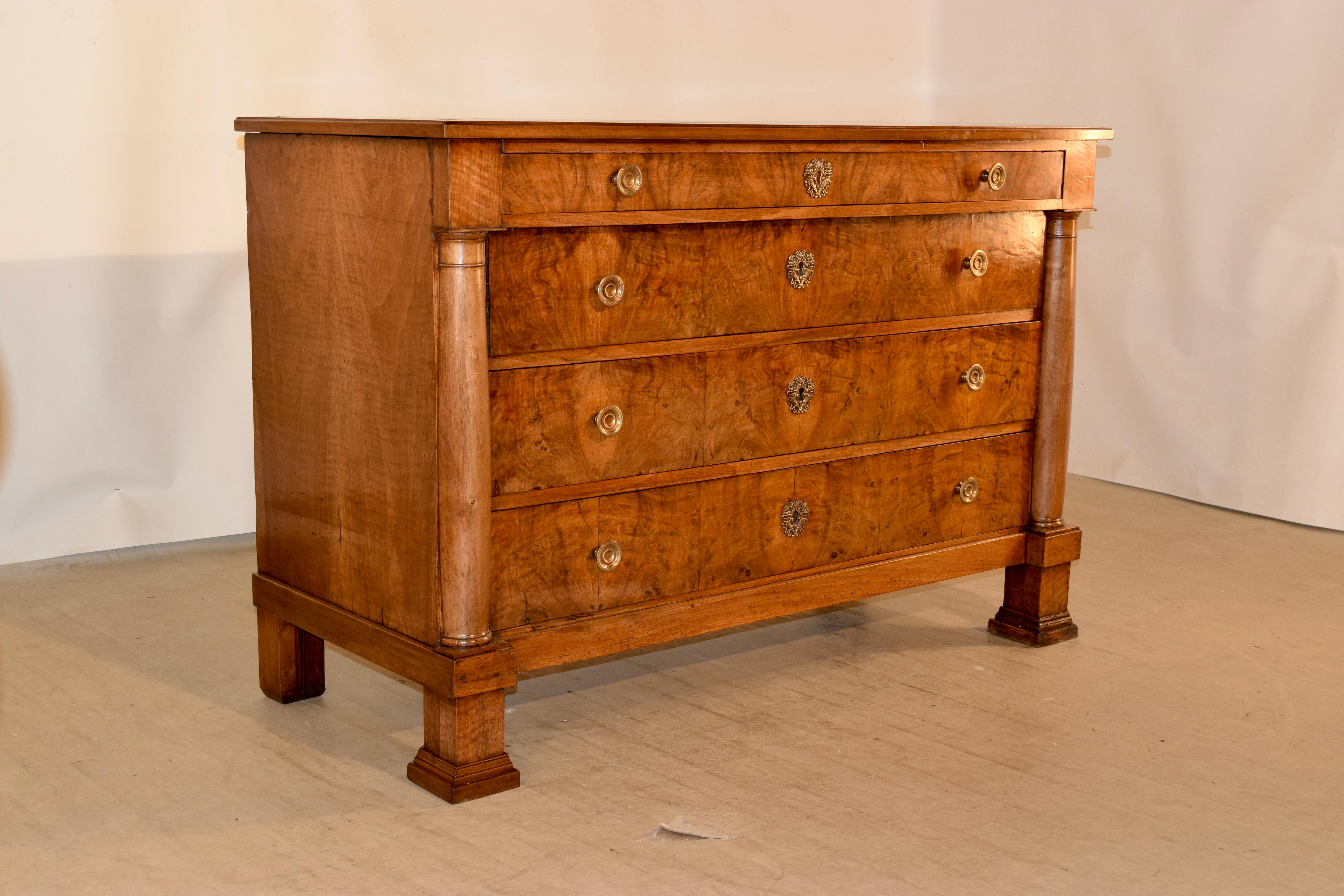 19th century French Empire commode from France made from walnut. The top is banded and has a beveled edge. This follows down to an apron containing a drawer over three drawers, all with burl drawer fronts. These are flanked by hand turned columns,