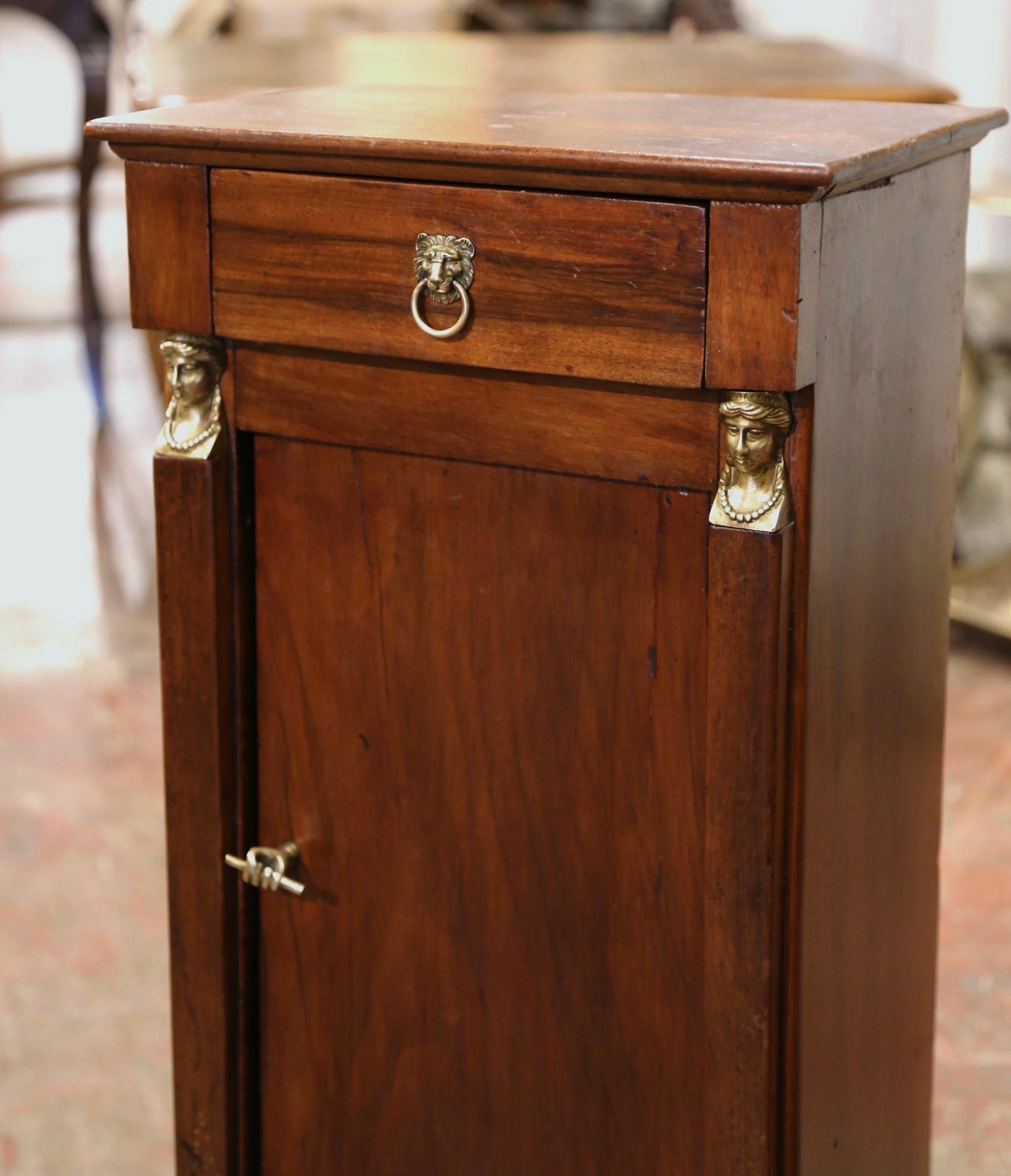 Crafted in France, circa 1880, the elegant antique cabinet is decorated with front square columns embellished with decorative brass mounts at the shoulder and the base, and ending with bracket feet over a wide bottom plinth. The small fruit wood
