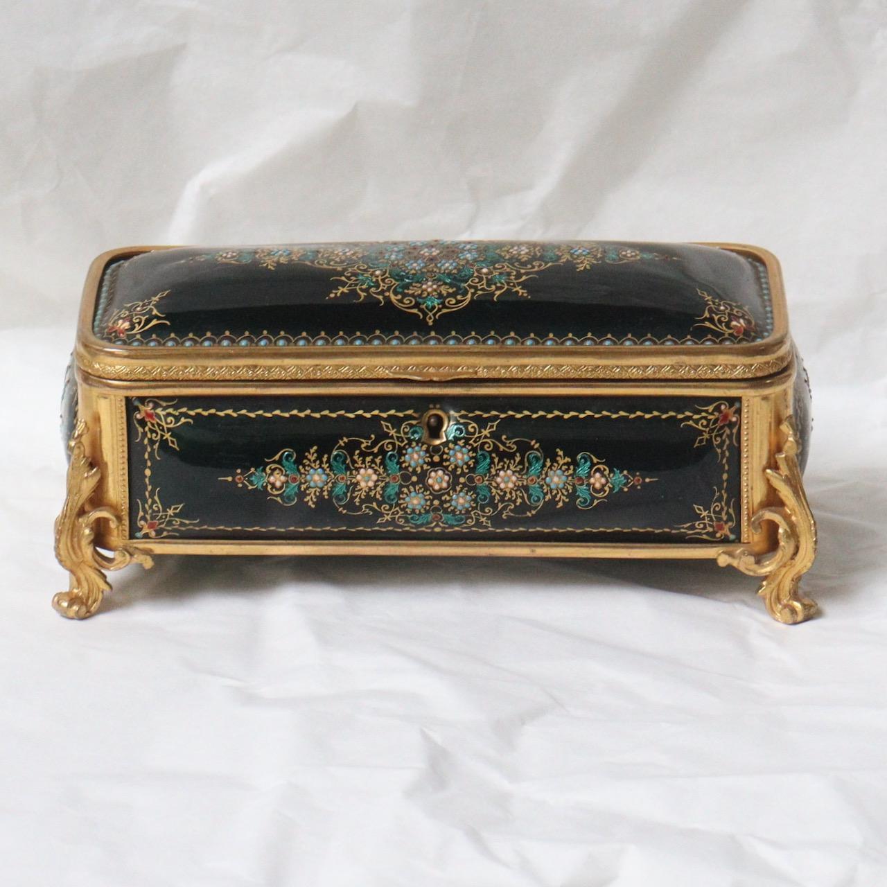 A French Napoléon III rectangular shape jewelry casket
With gilded bronzes and five hand-painted curved enamel plaques in gold and green on gold paillon, on a black emerald green background, decorated with reserves with white fleurons and lozenges,