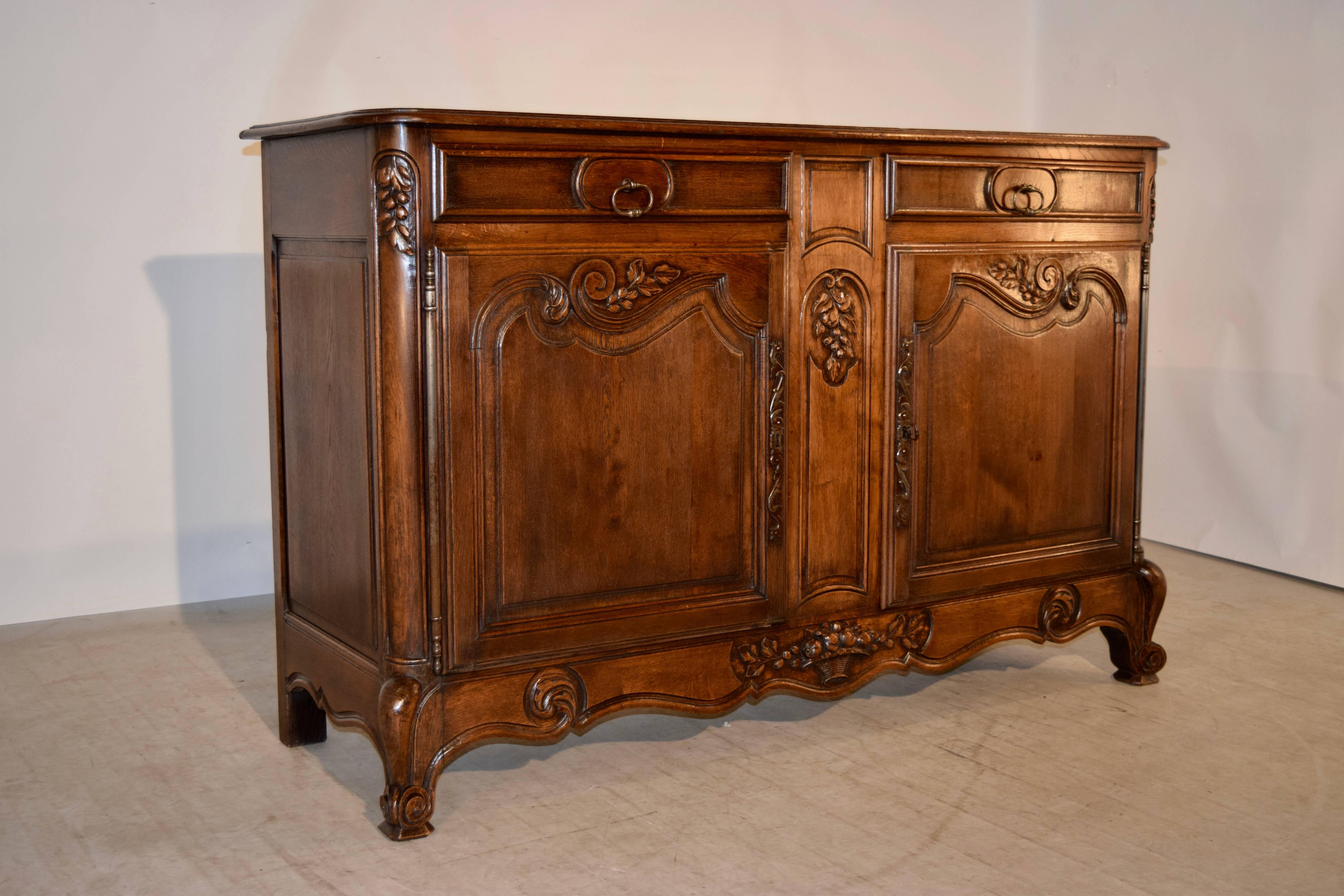 19th century oak enfilade from France. The top is bevelled around the edge and follows down to sides with raised panels and two drawers over two doors in the front, which open to reveal storage. The drawers are raised panelled and have nice molded