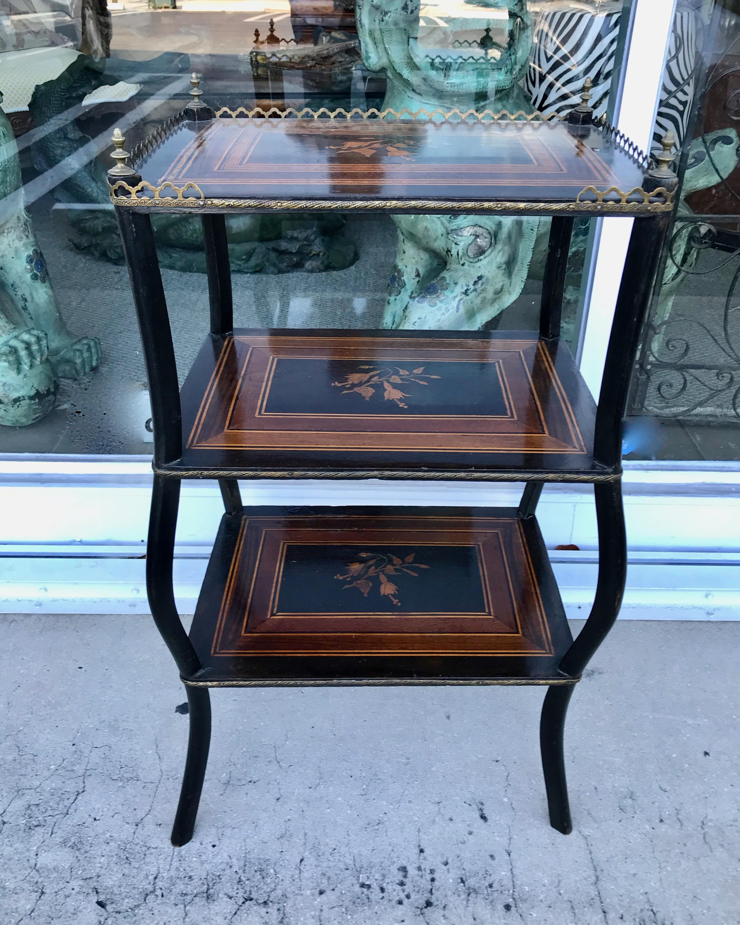 The stand is fashioned with 3 inlaid shelves, an upper brass gallery,
together with brass banding and finials. [ height measurement does
not include finials]
It is exquisitely inlaid with florals and ebonized accents.
Beautiful quality and