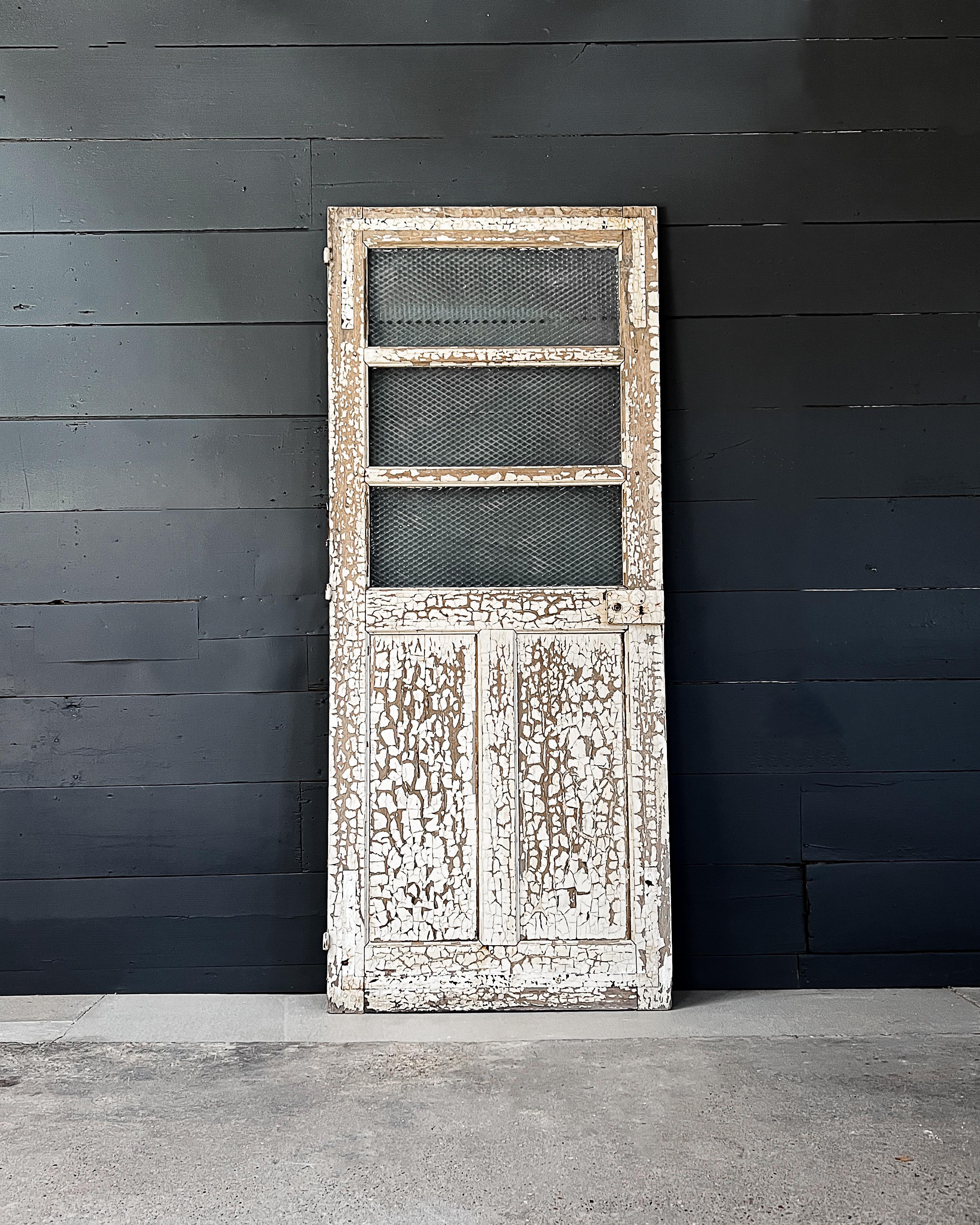 Turn of the century reclaimed French 3 lite over 2-panel configuration diamond glass exterior door. Install in your modern home to add old-world charm and character.

Salvaged in France.

Original white paint having a crackled texture covers one