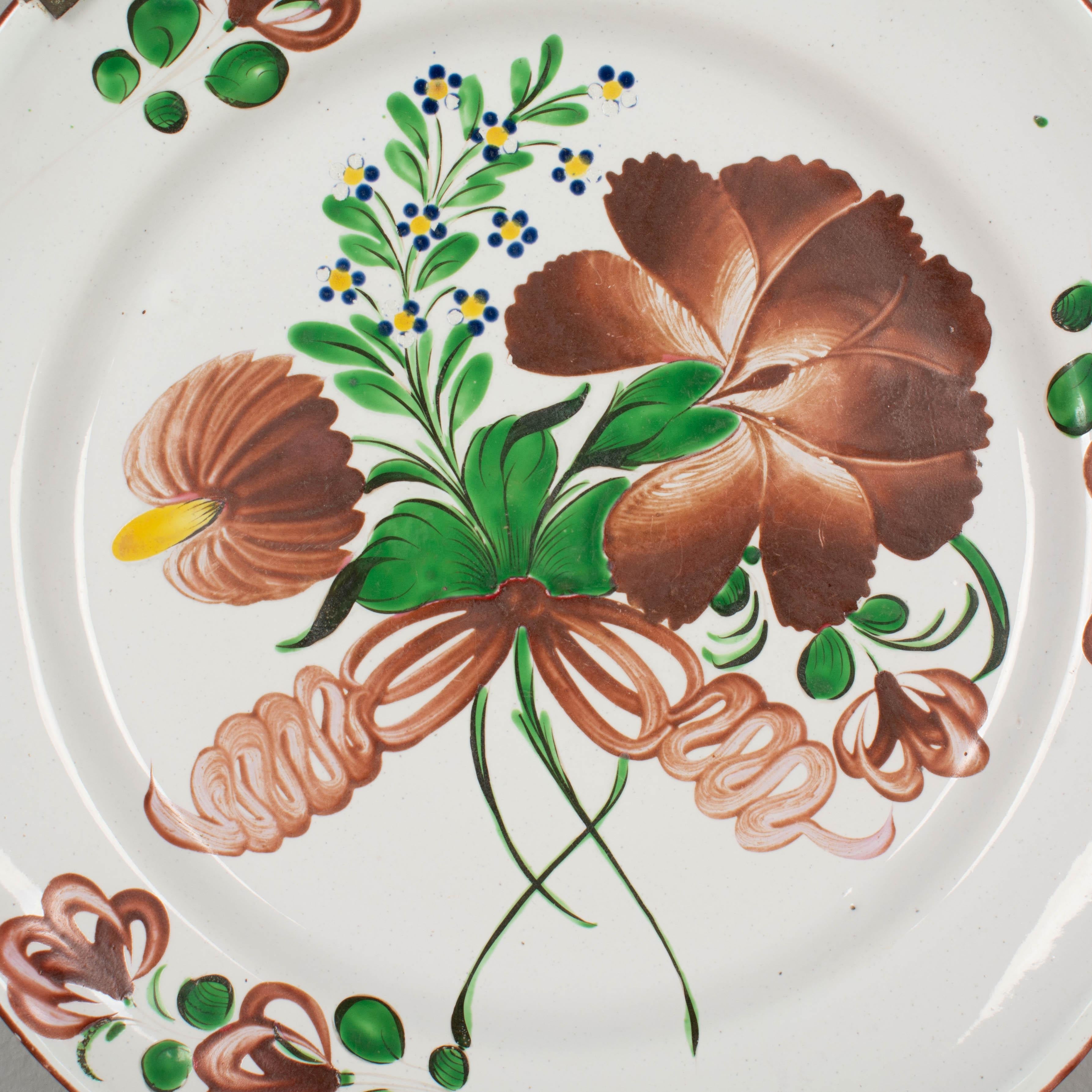 Cargador o fuente de loza francesa del siglo XIX con típica decoración floral burdeos pintada a mano procedente de San Clemente, en el este de Francia. Pequeñas pérdidas de vidriado. El antiguo colgador de placas de latón sigue sujeto.