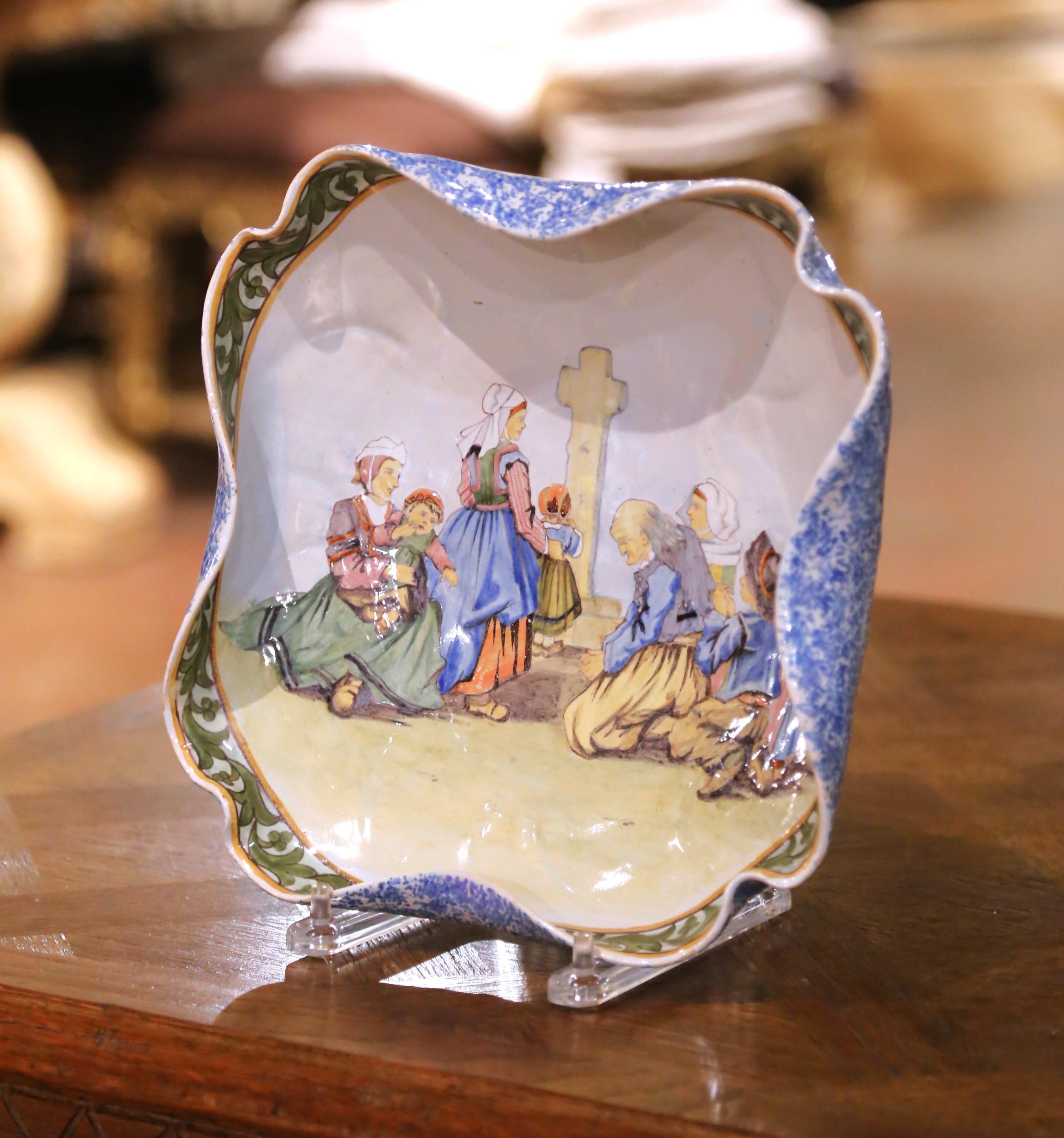 Bring color, narrative charm, and authentic Breton artistry to a wall or tabletop with this antique French faience dish from the renowned Porquier-Beau workshop in Quimper, Brittany. Hand-painted circa 1880–1890, the square dish with gently