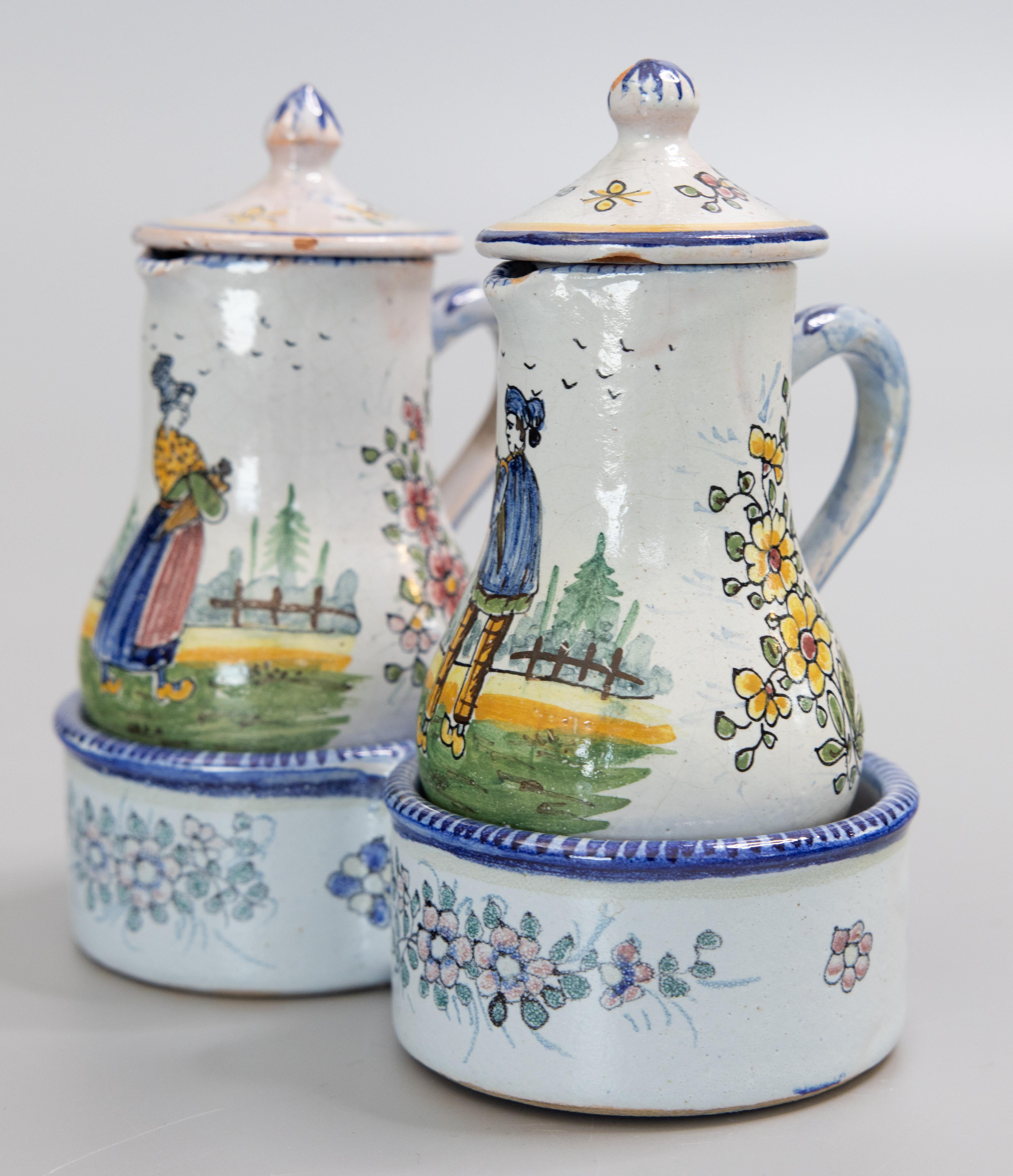 A charming 19th Century French Quimper faience oil and vinegar handled jugs cruet set and presentier double dish stand. Signed by the artist on the underside. The stand has a hand painted garland of flowers and holds two lidded ewers or small