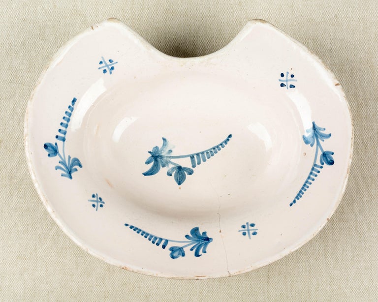 A 19th century French faience shaving bowl, hand-painted with blue flowers. Hairline crack.