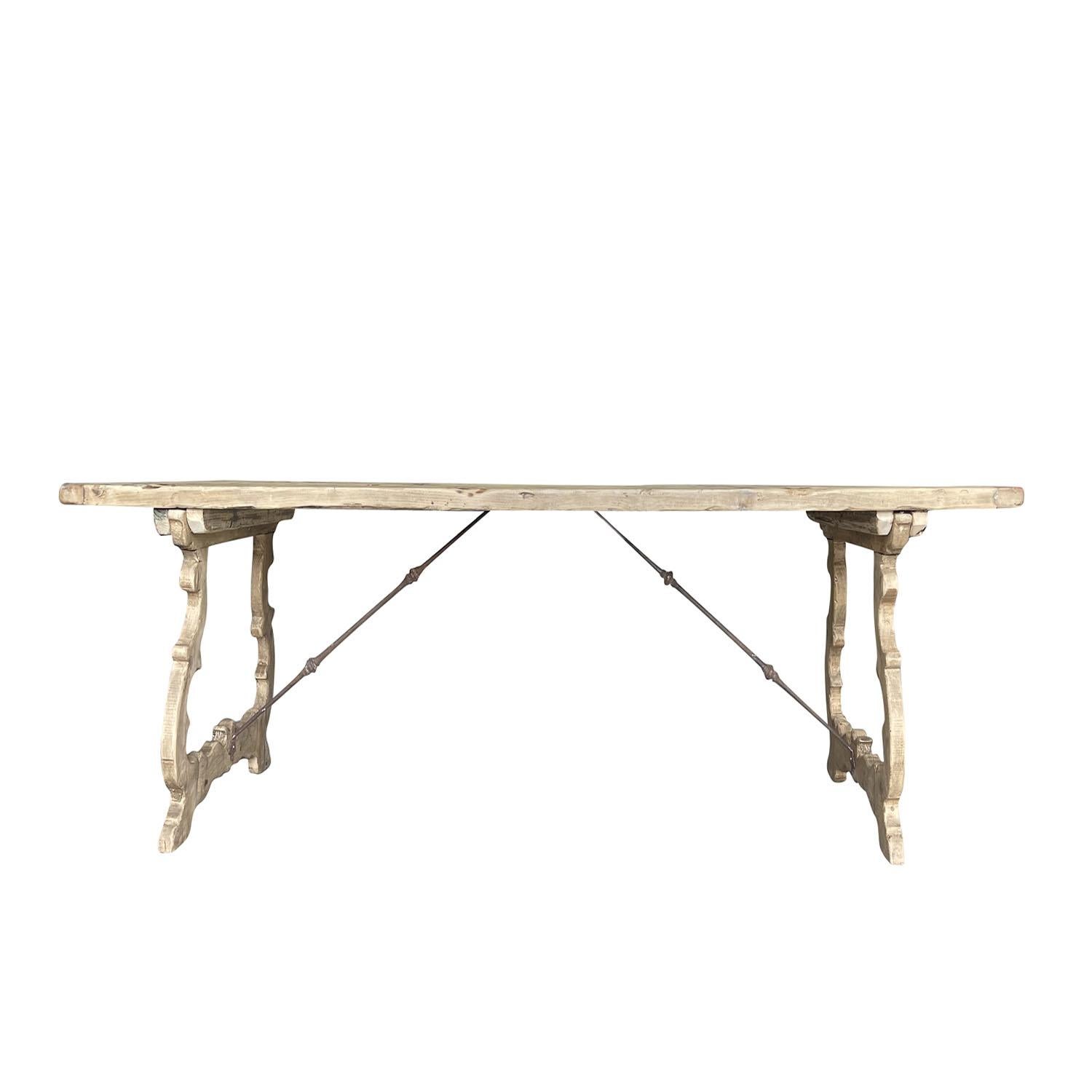 Table de salle à manger rectangulaire ancienne en bois de pin blanchi à la main, en bon état. Le plateau en planches épaisses repose sur une double base en forme de lyre et est renforcé par deux brancards en métal forgé à la main. La patine antique
