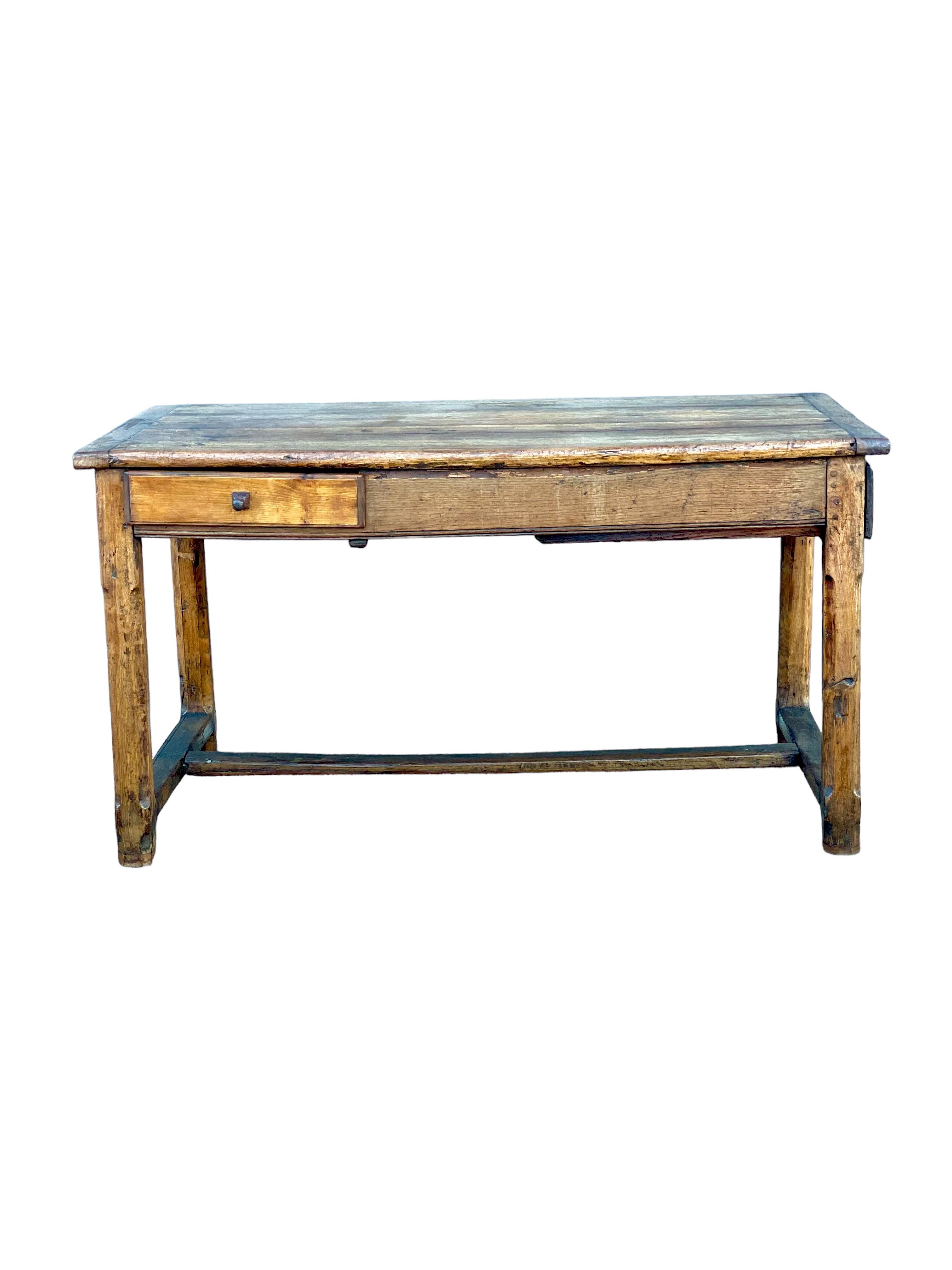A rectangular antique farmhouse table, full of character, in solid, roughly-hewn oak, with cleated top, side and end drawers and entretoise connecting its chamfered square-section legs. Shows a real history of kitchen work with its faded top and
