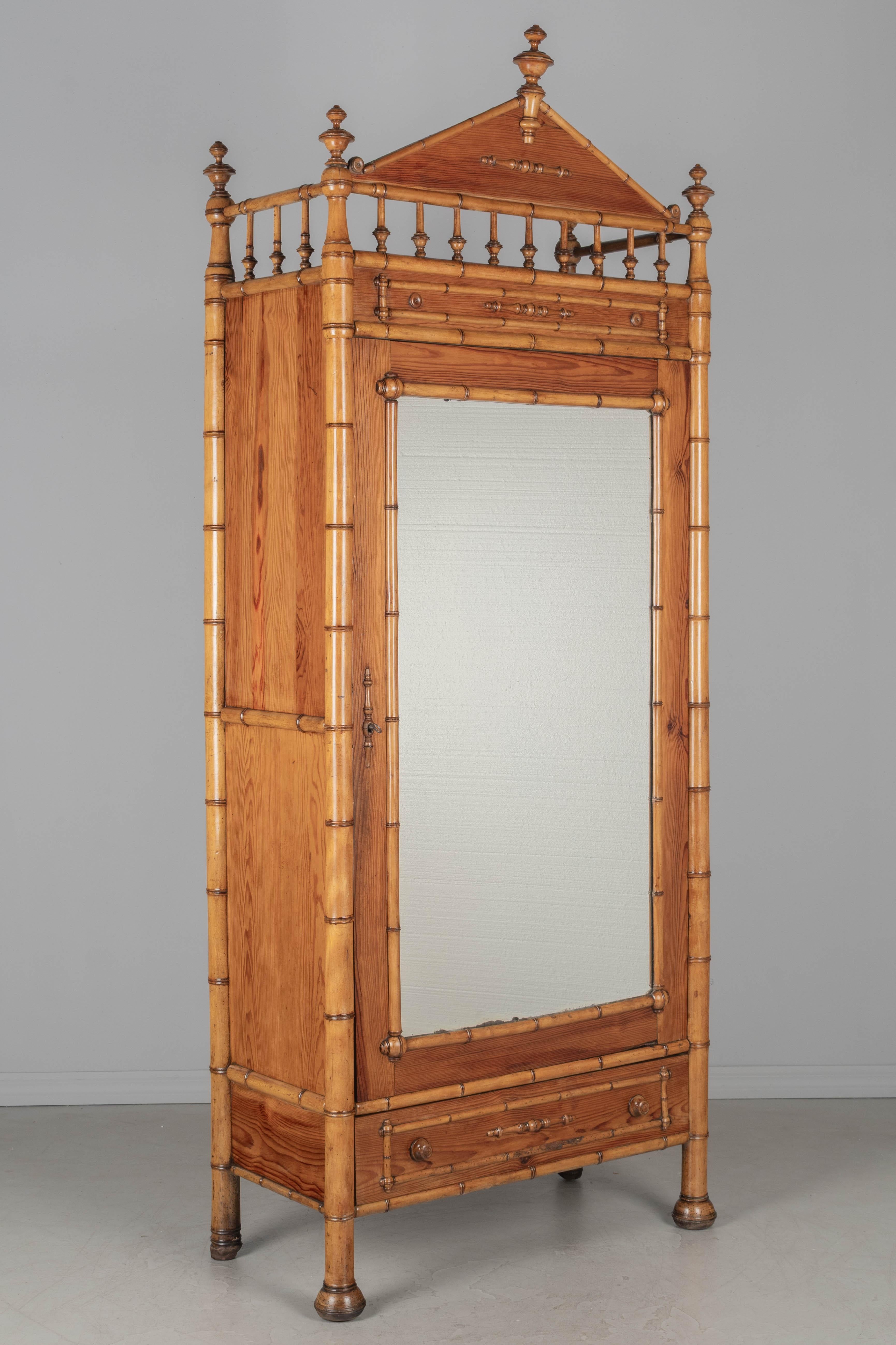 Armoire française du 19e siècle en faux bambou, faite en pitch pin avec des détails en faux bambou en cerisier massif. La porte en miroir biseauté s'ouvre sur un intérieur doté de deux étagères réglables et d'une étagère fixe. Serrures et clés en