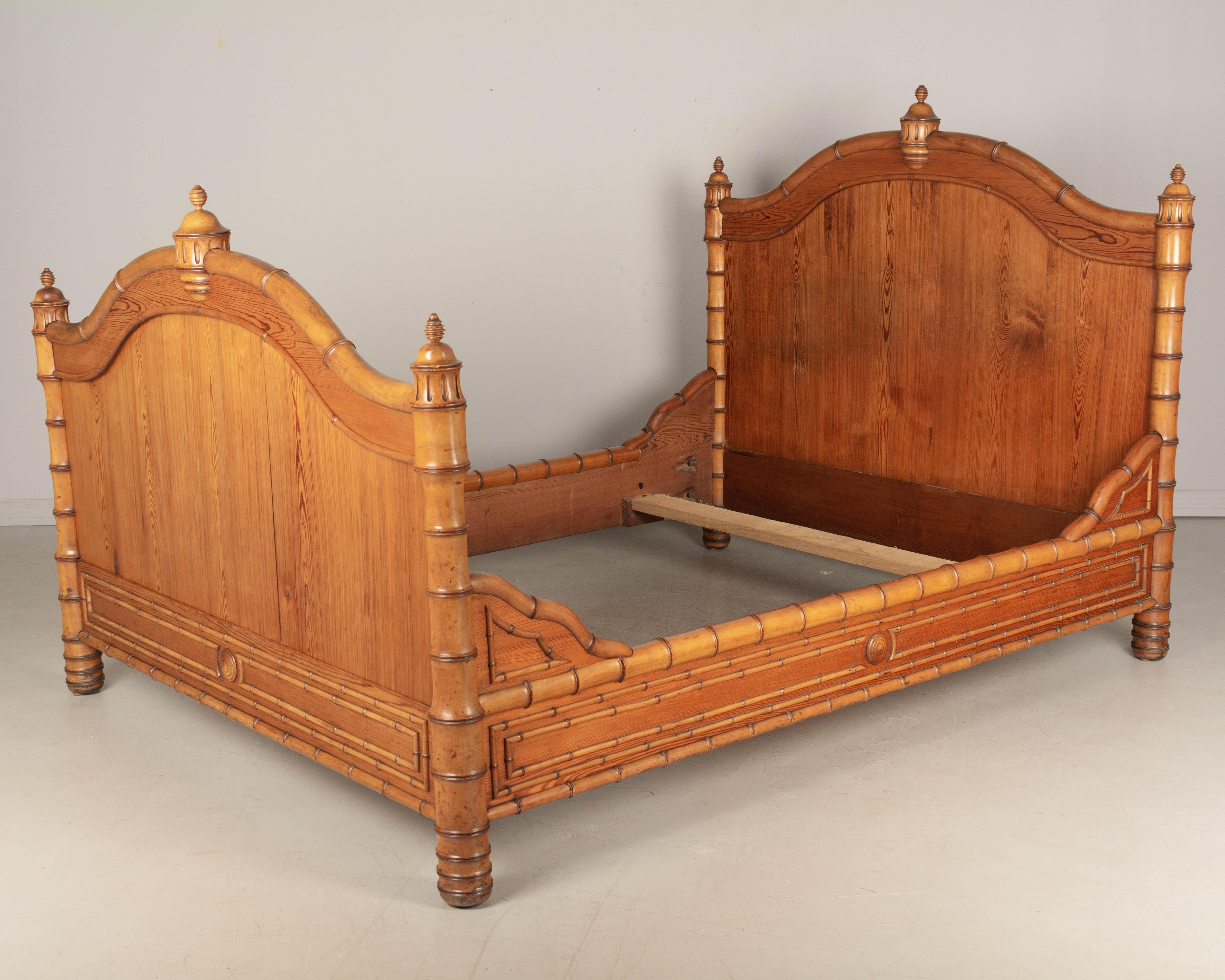 A good quality 19th century French faux bamboo bed, handcrafted of pitch pine with carved cherry wood decorative trim. Large turned bedposts and center decorations. Nice faux bamboo pattern trim. Two small pieces of trim missing on the side rails.