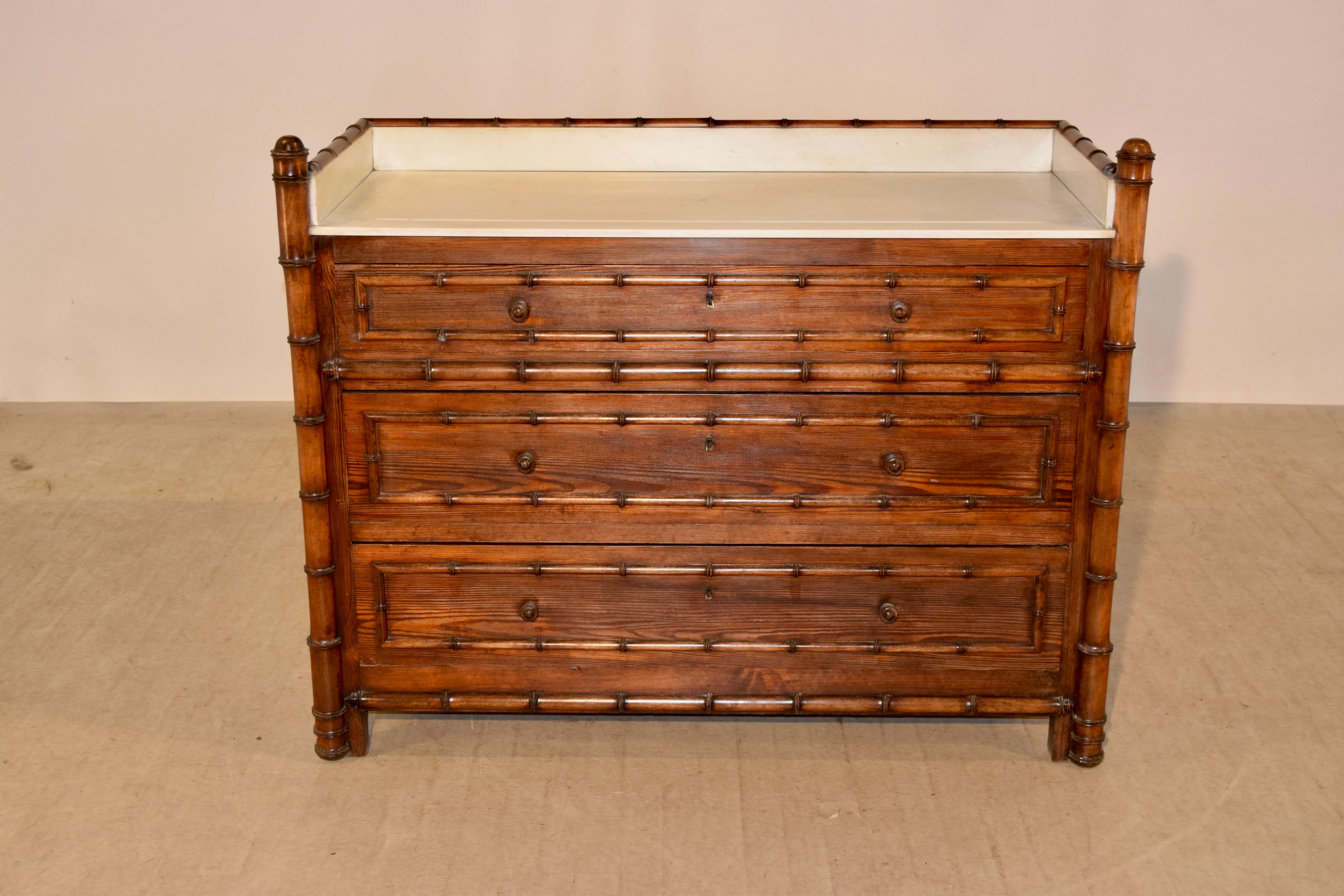 19th century, French faux bamboo chest with marble top. The top is decorated with hand-turned finials and a three sided gallery, which are all lined with marble following down to a marble top over three drawers, all of which are banded with faux