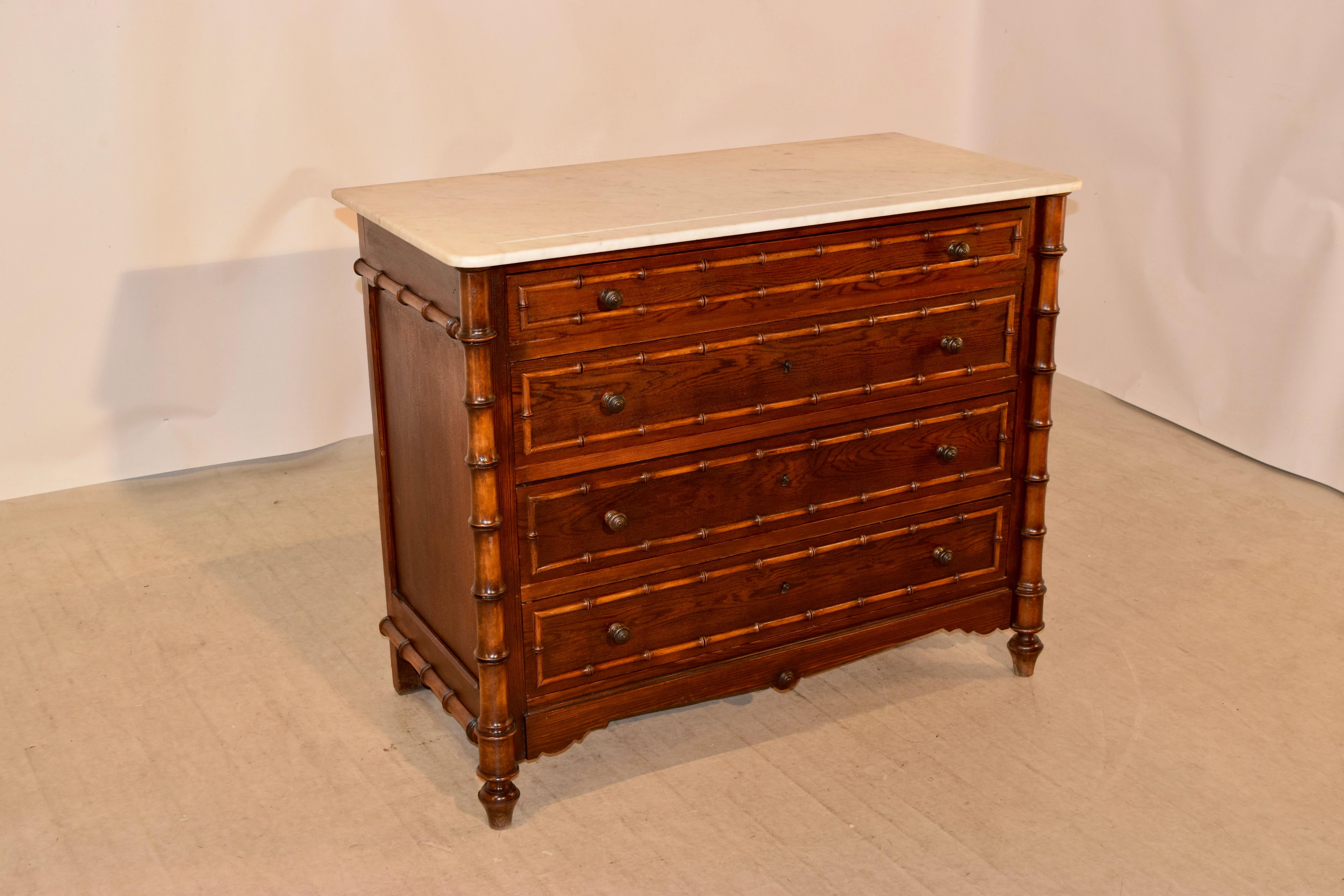19th century faux bamboo chest of drawers from France with a white marble top resting atop a pine and cherry case with simple paneled sides with hand-turned molding in the form of bamboo. The front of the case has four drawers, also with applied