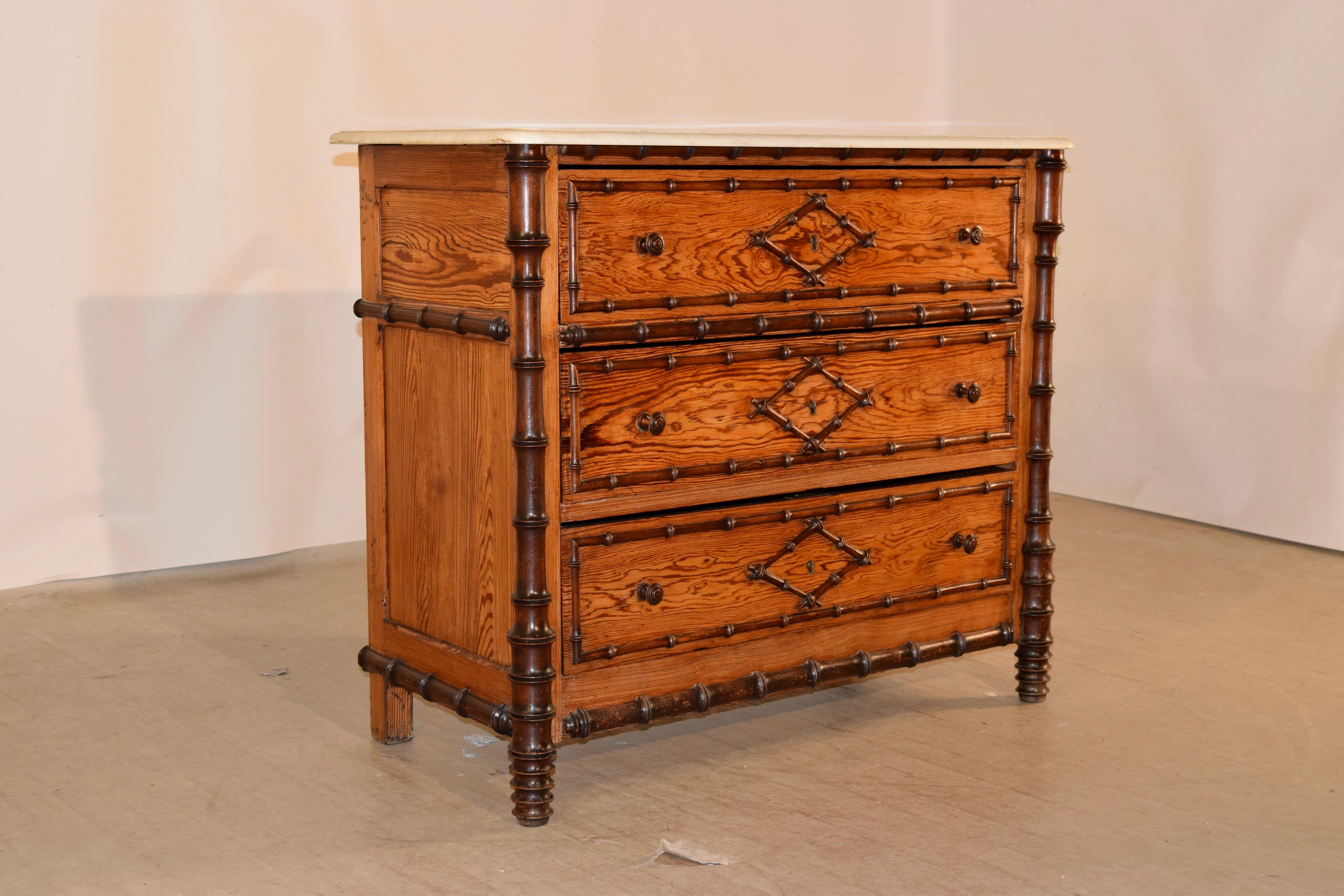 19th century faux bamboo chest of drawers from France with a removable Carrara marble top, following down to a pitch pine case with hand turned cherry wood applied moldings. The case has three drawers flanked by hand turned cherry legs which are