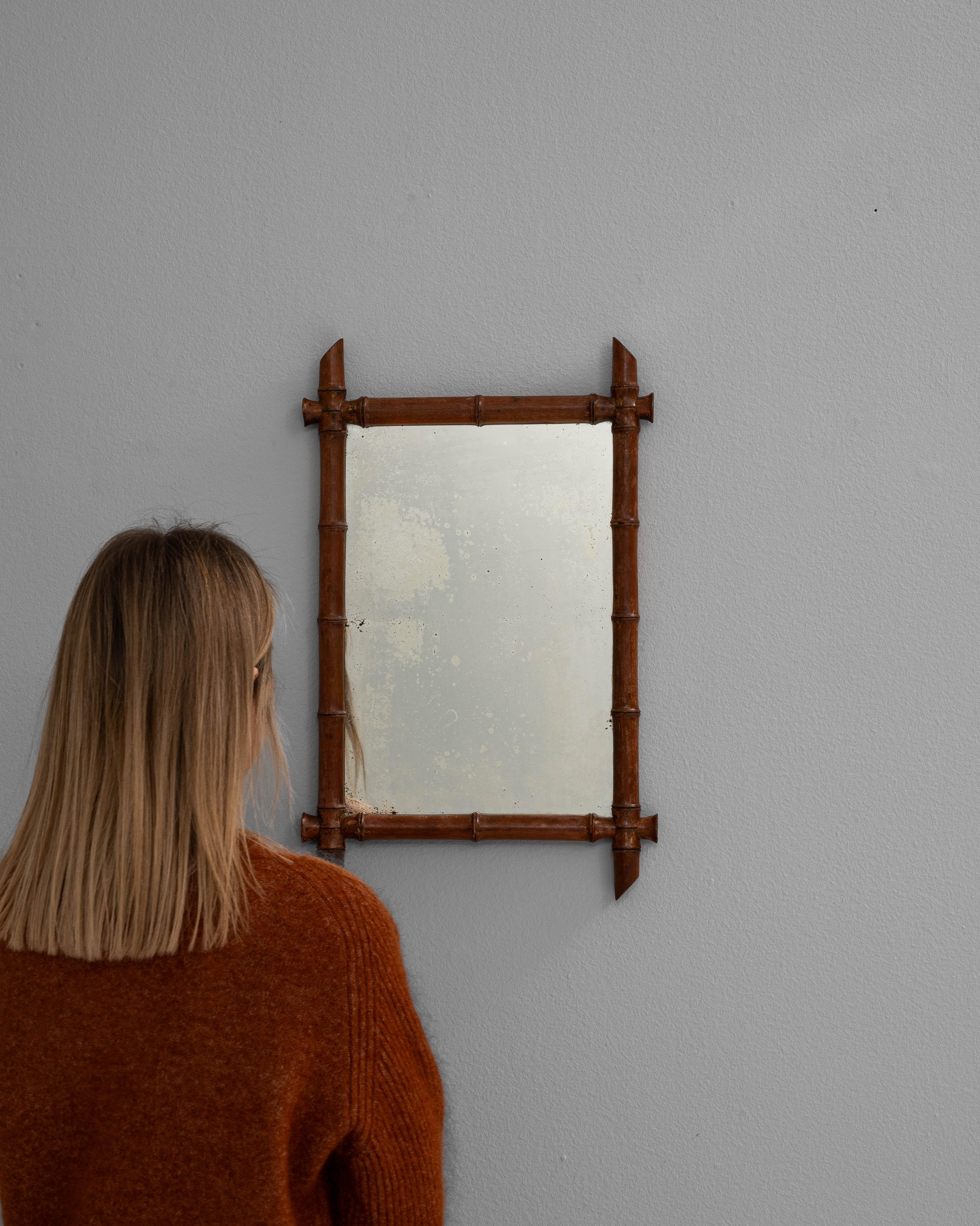Fabriqué à la fin des années 1800, ce miroir français en faux bambou présente un cadre en bois sculpté à la main qui imite l'apparence du bambou, un motif populaire pendant le mouvement du Japonisme en Europe. La riche finition brun-rouge met en