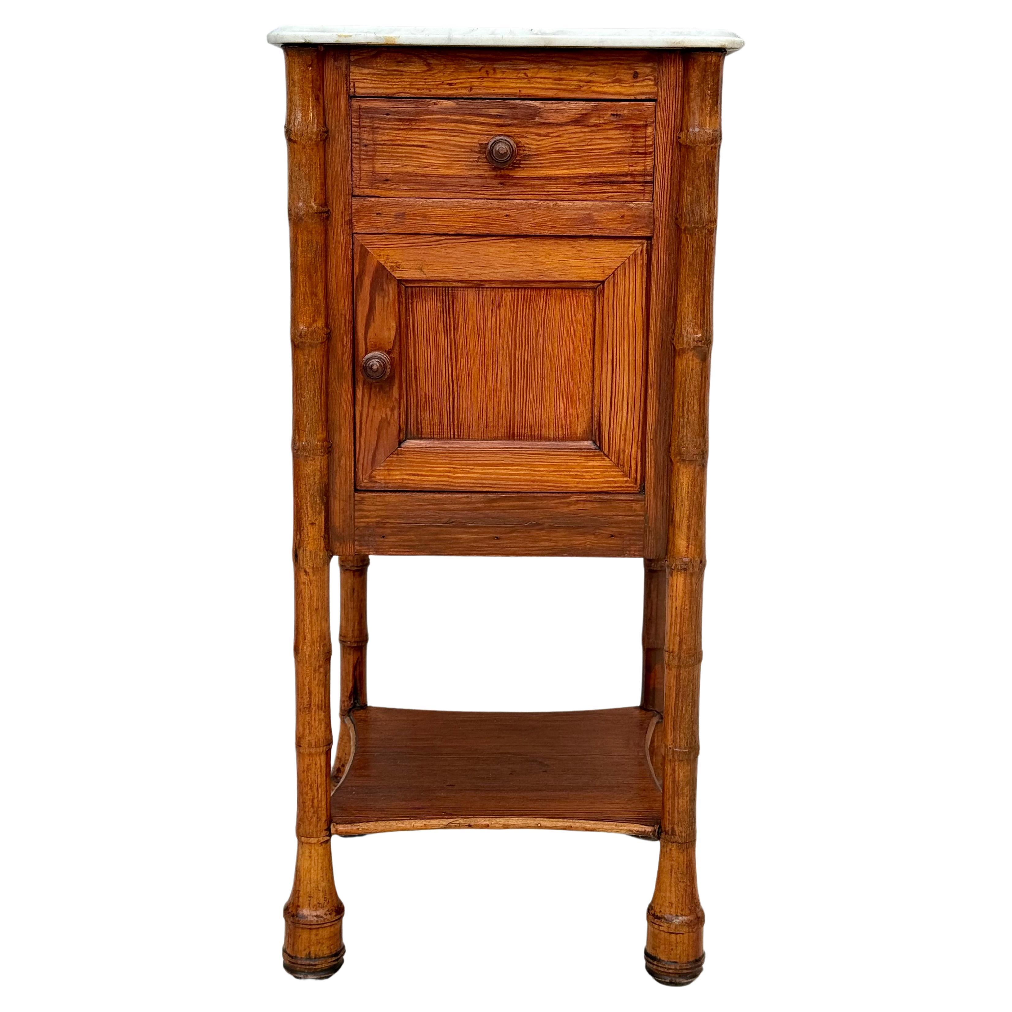 Charming 19th century French faux bamboo nightstand or side table with white marble top. Table features a top drawer over a door with shelf, and an open bottom shelf. Perfect for bedroom night stand or in bathroom as extra storage. 