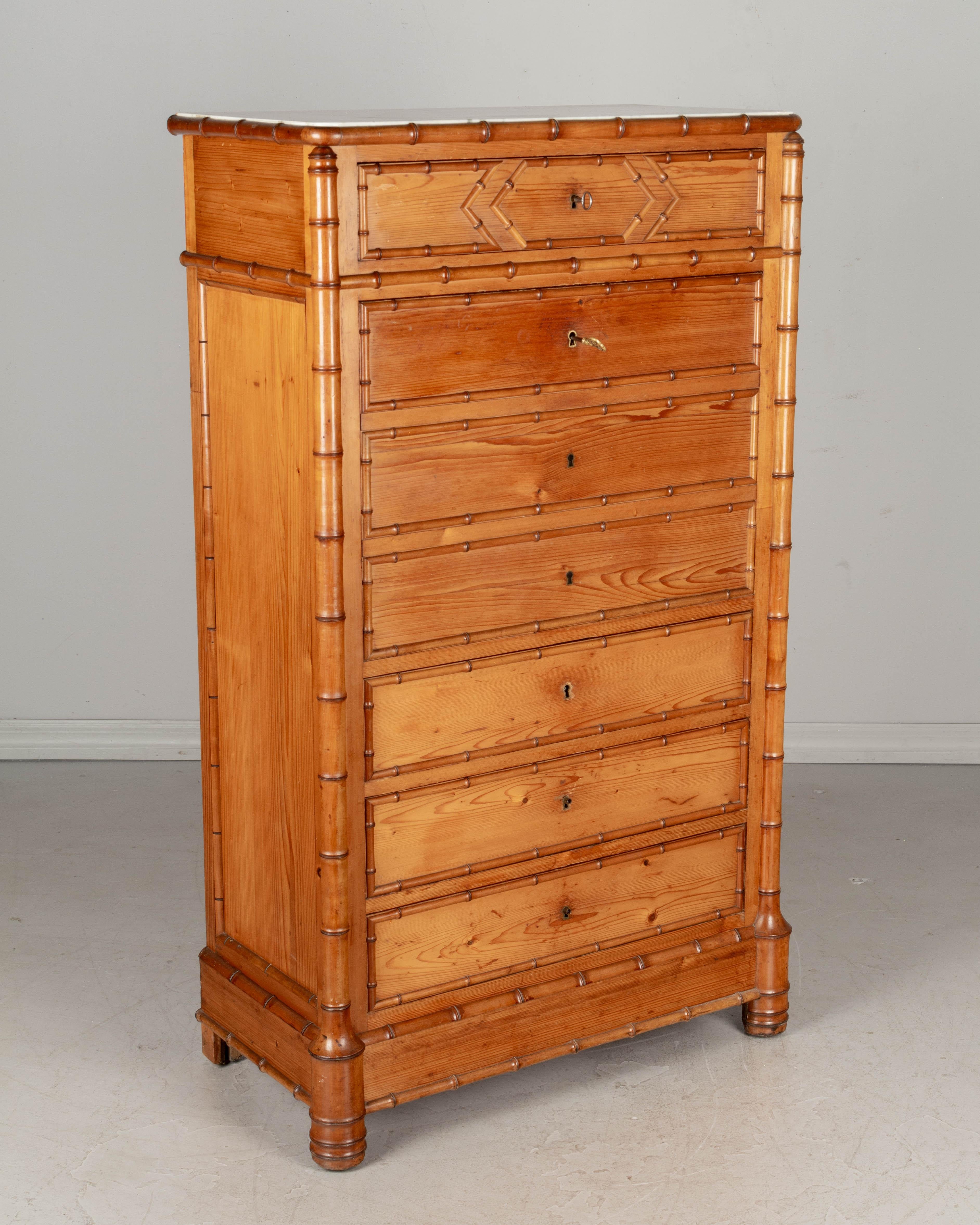 A 19th century French secrétaire à abattant, or drop front secretary desk, with the case made of pine and the faux bamboo details made of turned cherry wood. Four dovetailed drawers with working locks and two keys and three false drawers create the