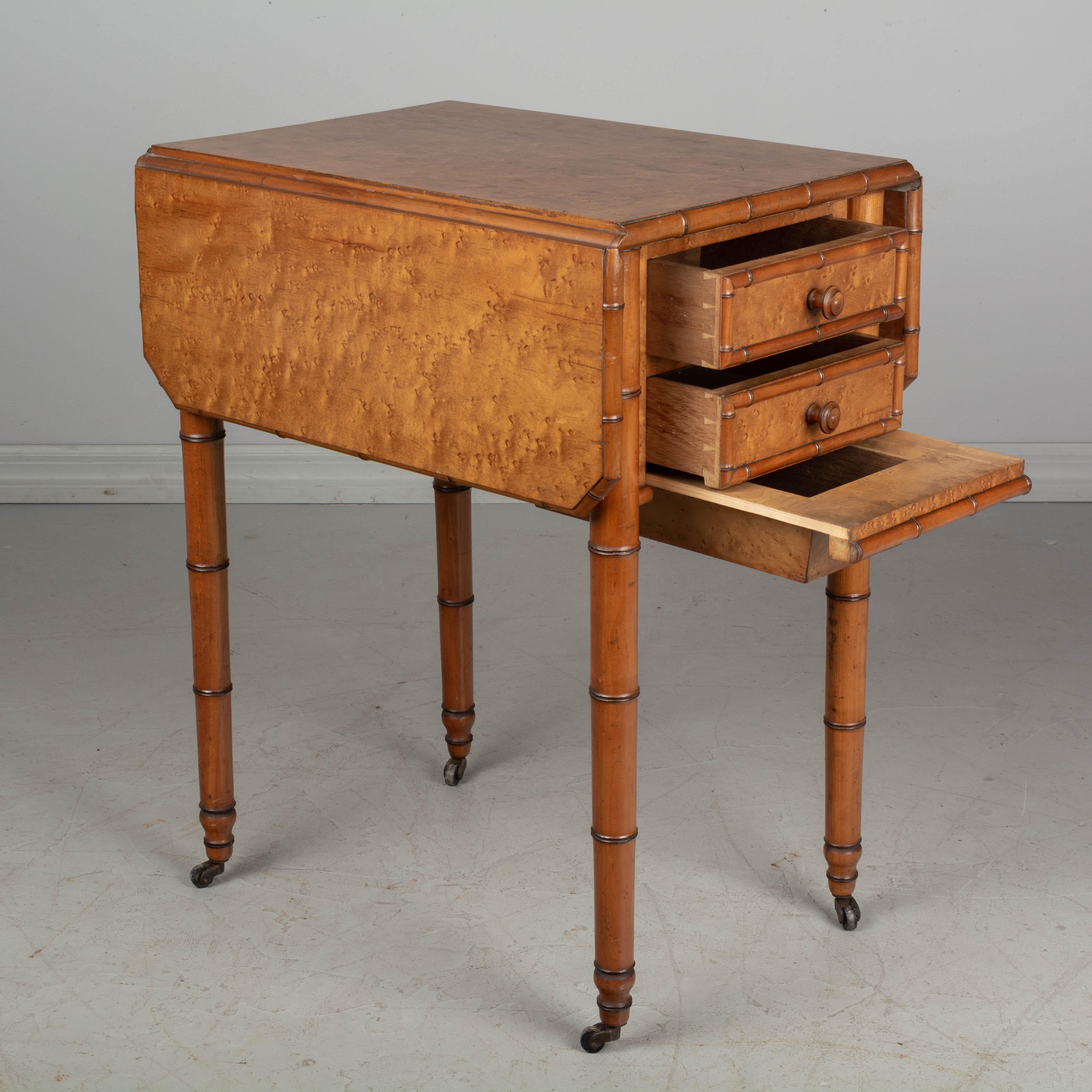 A 19th century French faux bamboo bedside table, or nightstand, made of cherrywood and veneer of bird's-eye maple. This is a versatile side table with a drop leaf top, two dovetailed drawers one side and a small hidden drawer underneath. The