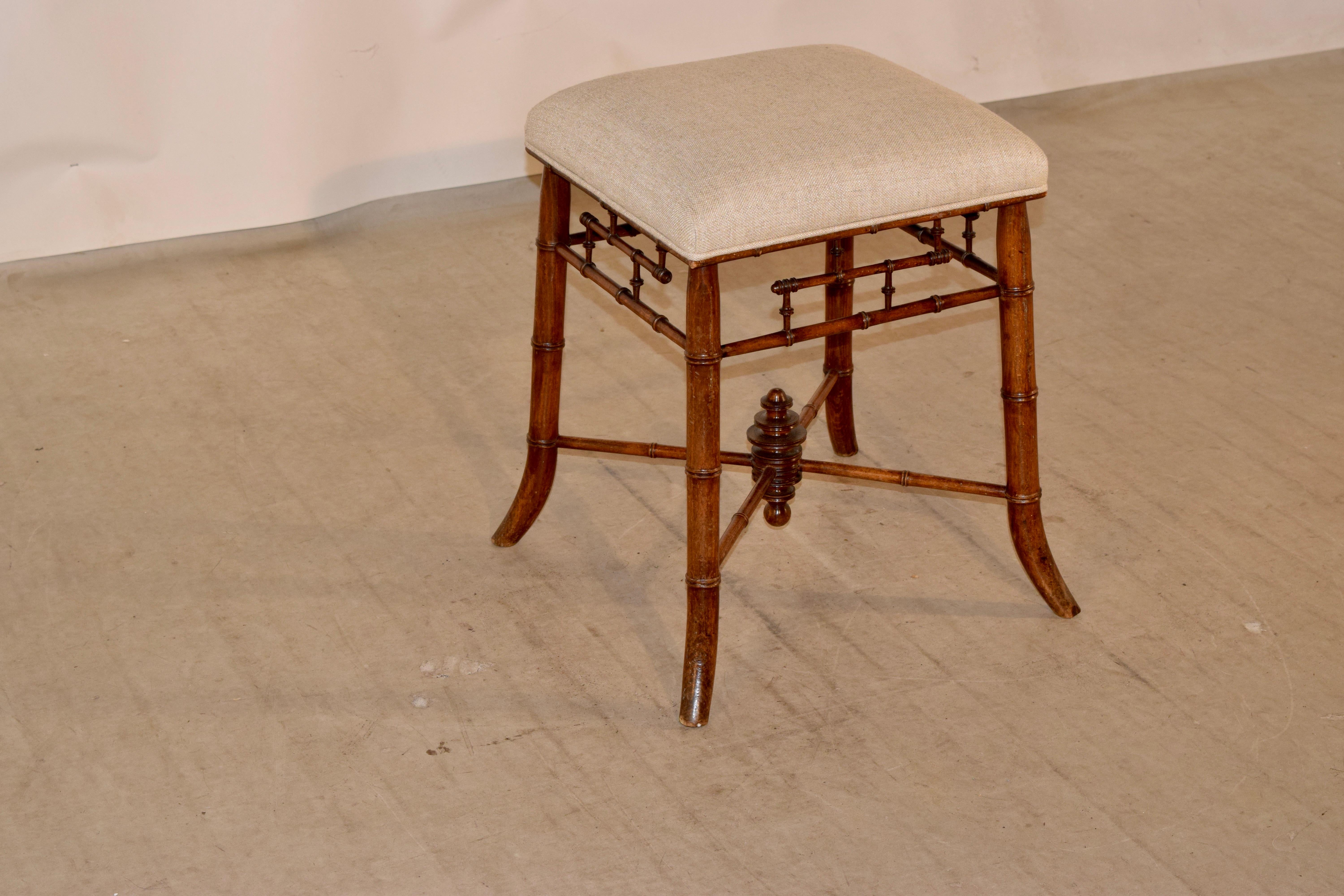 19th century French stool made from cherry. The seat has been newly upholstered in linen and is supported on a solid cherry frame with hand-turned faux bamboo legs, stretchers, and apron design. The legs are splayed for a graceful design.