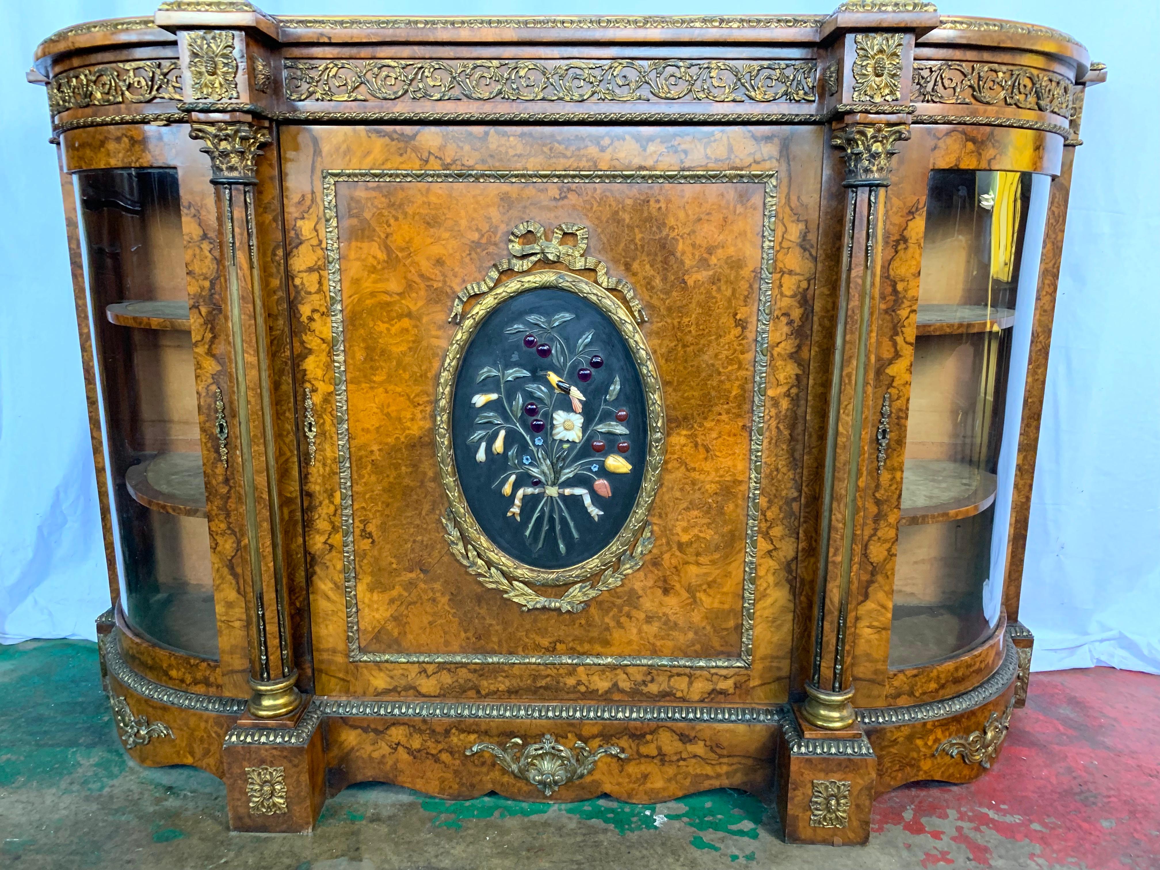 A good 19th century French figured walnut Credenza. The central panelled door inset with Pietra Dura fruit. Flanked by glazed shelves. Ormolu mounts throughout.