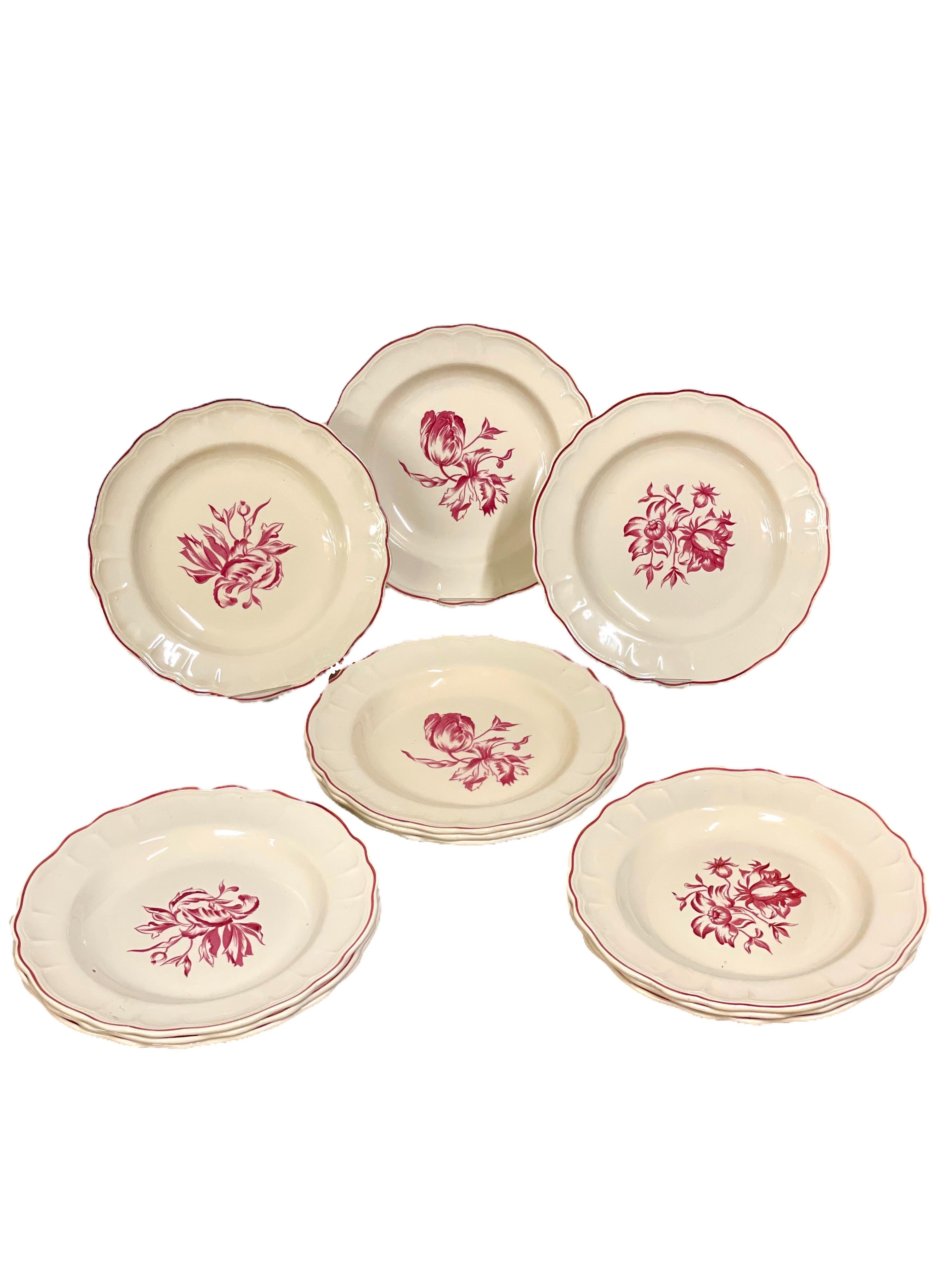 Beautiful dinner service in fine creamware, decorated with a red transferware print in three different floral designs. Each piece in the set has a delicately scalloped rim, highlighted with a hand-painted red border. The set comprises 12 dinner