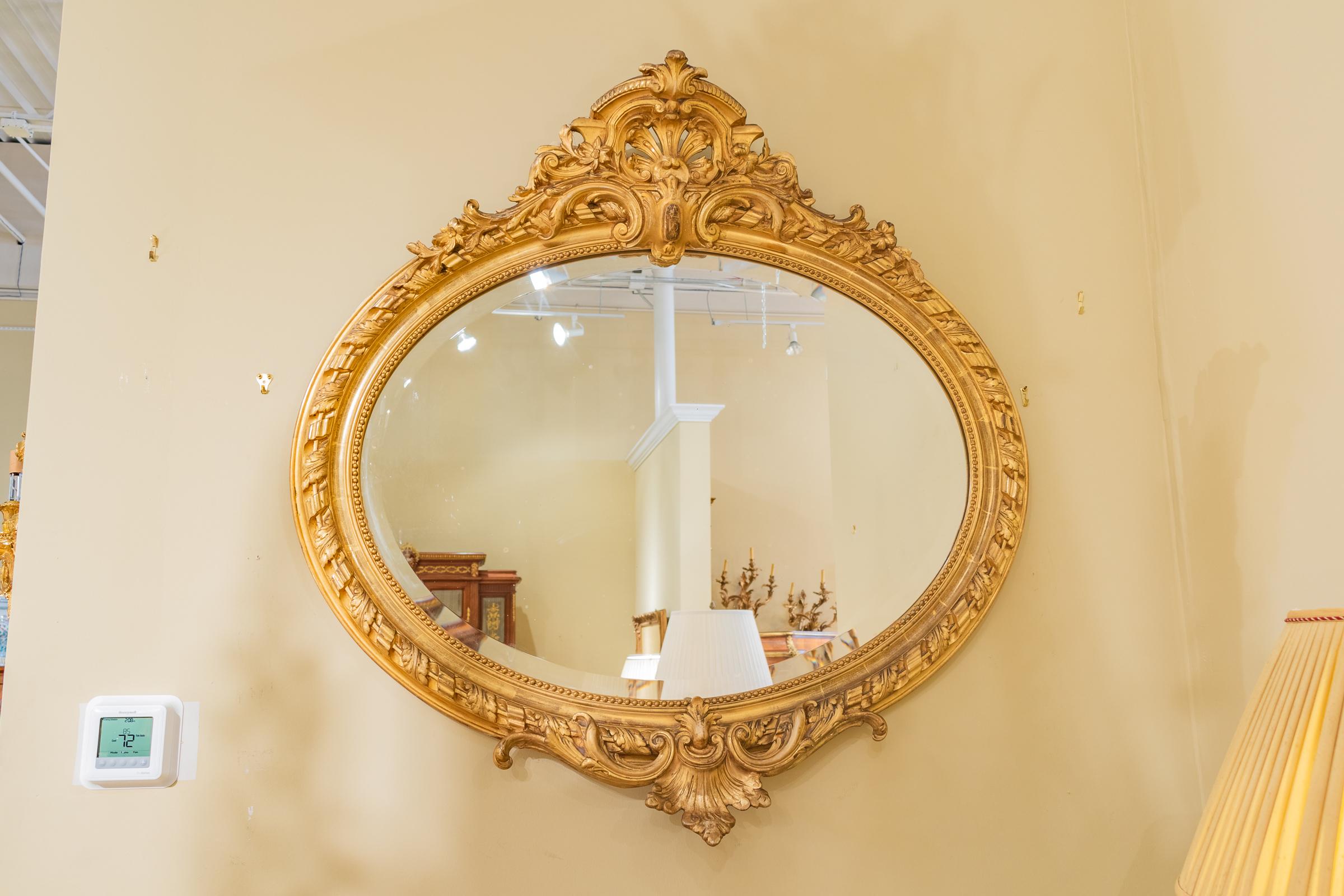 Beautifully hand carved and gilt French 19th century Louis XV oval mantel (fireplace) mirror. Beveled glass with fine detailed carving. Water gilding still evident on the carving.