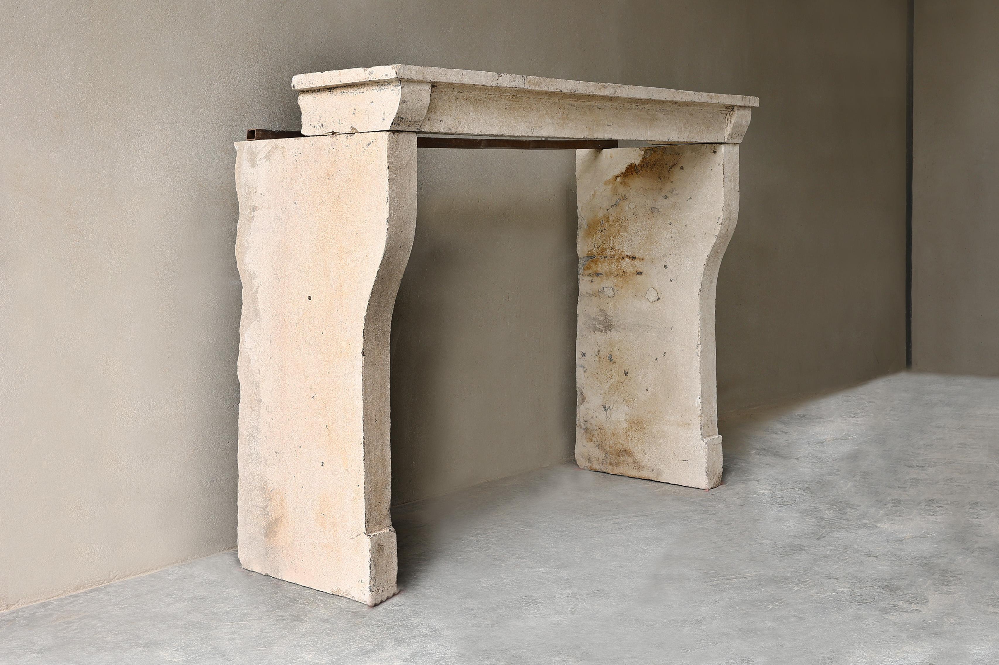 Antique compact fireplace of French limestone from the 19th century in Campagnarde style! A rustic fireplace that is compact in size and fits in many interiors. The fireplace has slightly curved legs and a slender appearance.