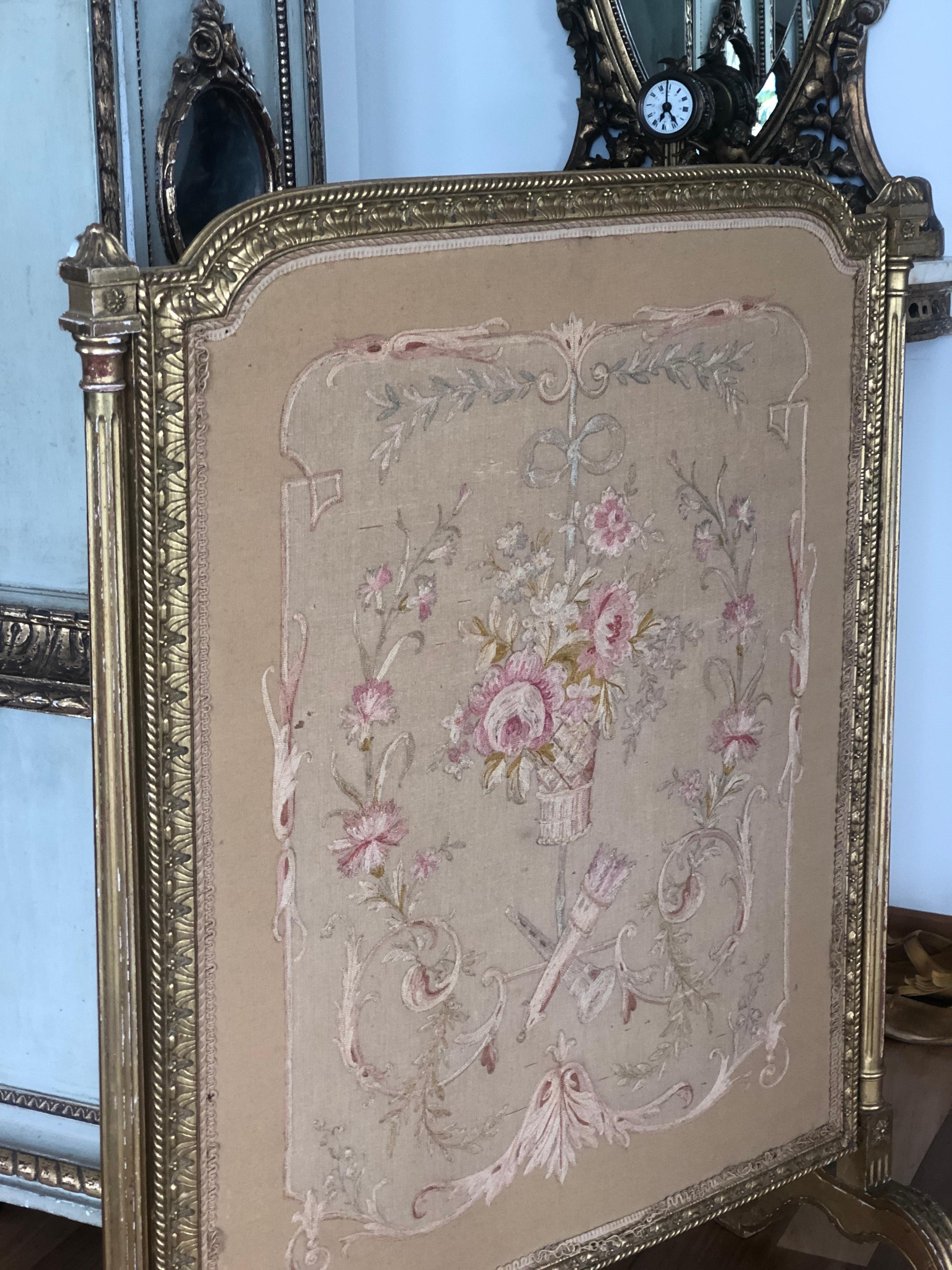 Eleganter Kaminschirm im Louis XVI-Stil aus vergoldetem Holz mit handgeschnitztem Rahmen, gepolstert mit authentischem Seidentapetenstoff in hellen Farben und floralen Motiven.
Frankreich, um 1860.
 