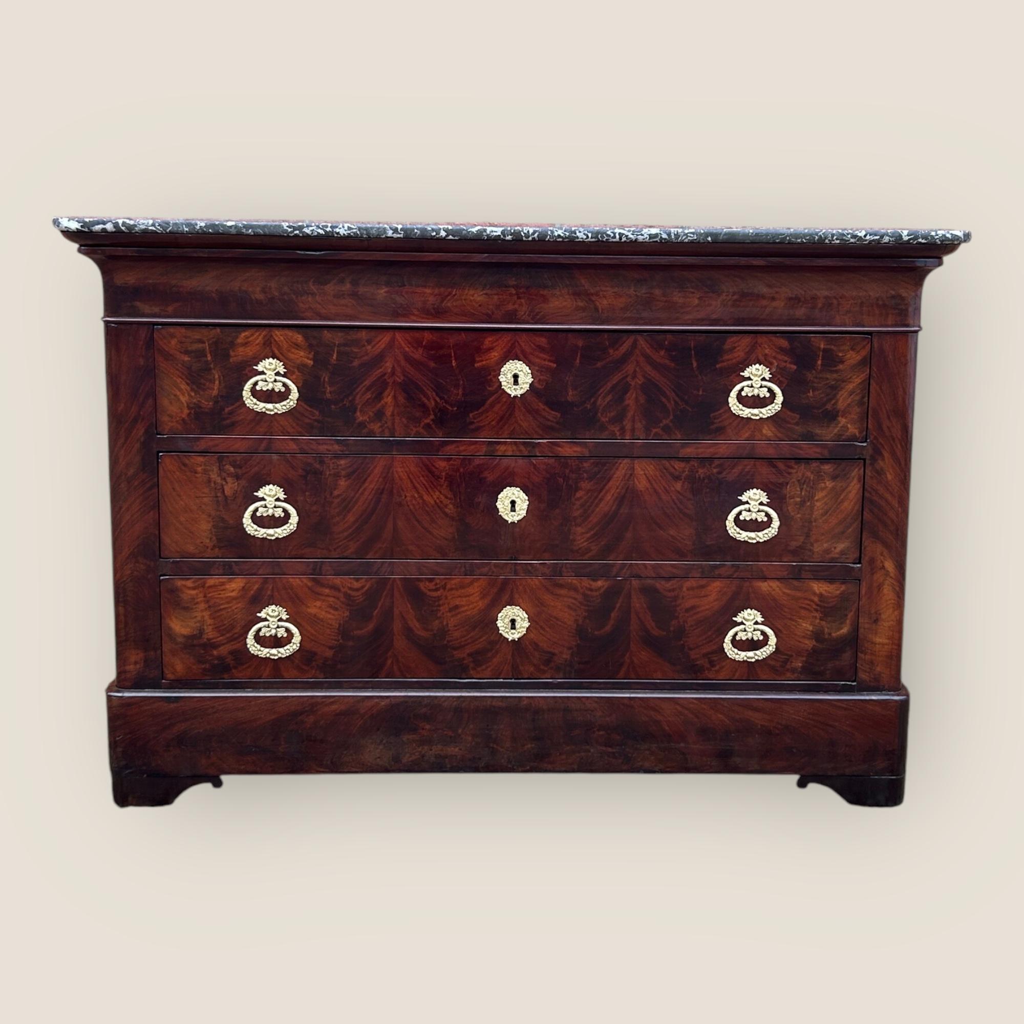 Una bellissima commode francese in mogano a fiamma del XIX secolo, risalente al periodo vittoriano. Il piano rettangolare, con bordi arrotondati, è realizzato in solido marmo grigio. Ci sono 3 cassetti nella parte anteriore, dotati di maniglie e