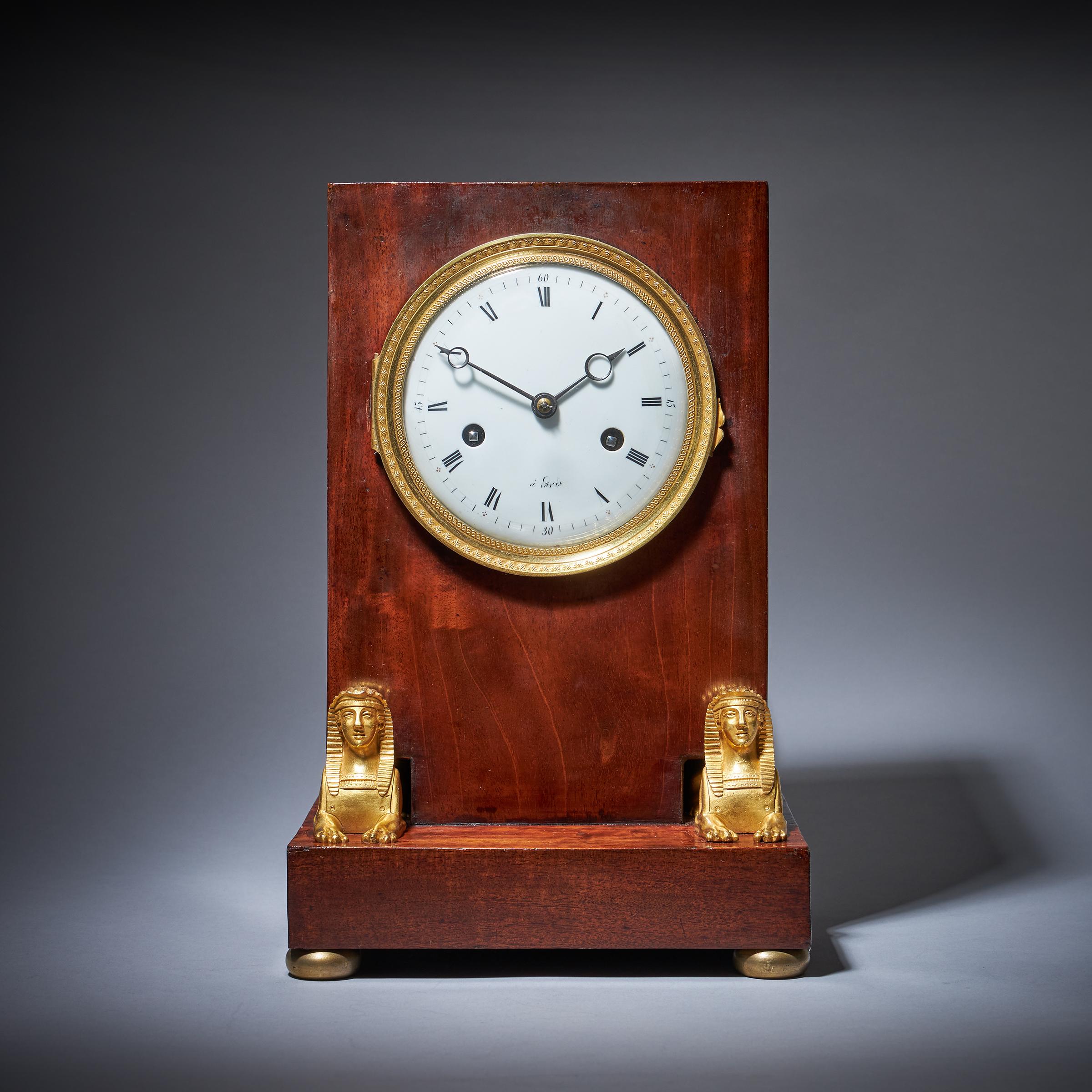Superbe horloge de cheminée du 19e siècle en acajou flammé d'époque Napoléon Empire, de style égyptien.

Cette horloge a été produite à l'époque de l'Empire français, dans le premier quart du XIXe siècle. La campagne de Napoléon en Égypte a suscité