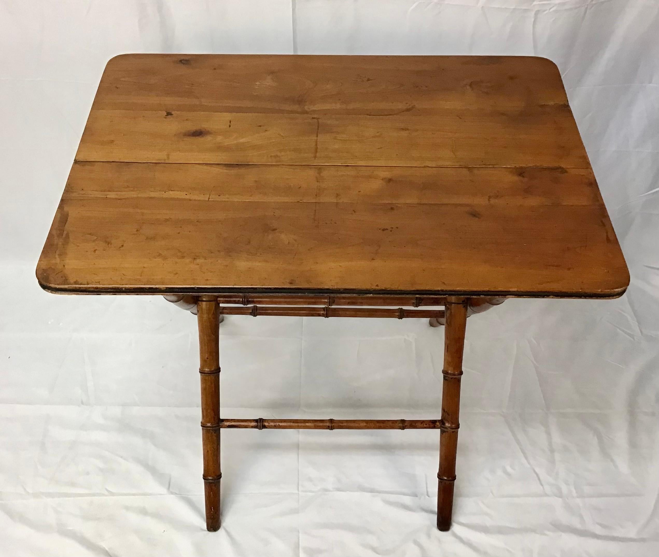 This is a French 19th century faux bamboo table. The top edge is carved faux bamboo trim. The legs connected by a stretcher are a darker wood made to resemble bamboo. They will slide in one direction so the top folds down and can be stored against a