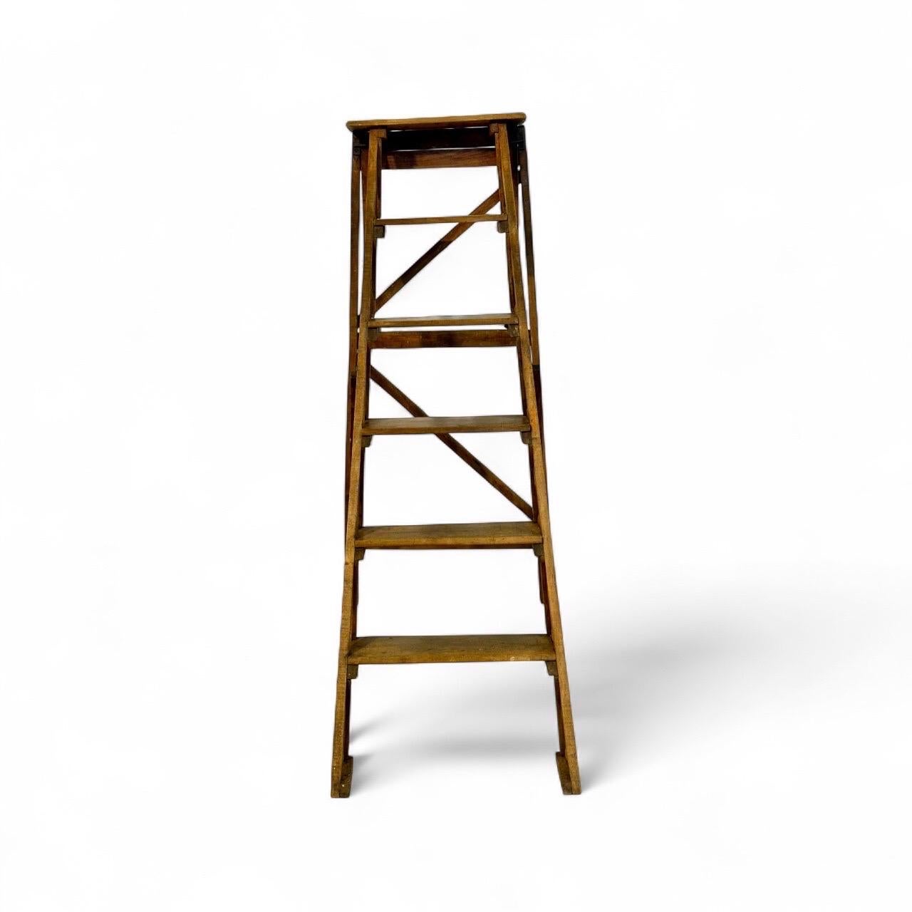 Esta elegante escalera plegable francesa, fabricada en nogal y fechada a finales del siglo XIX, es una pieza rara que combina practicidad y refinada artesanía. Con seis peldaños y una amplia plataforma superior, se diseñó originalmente para su uso