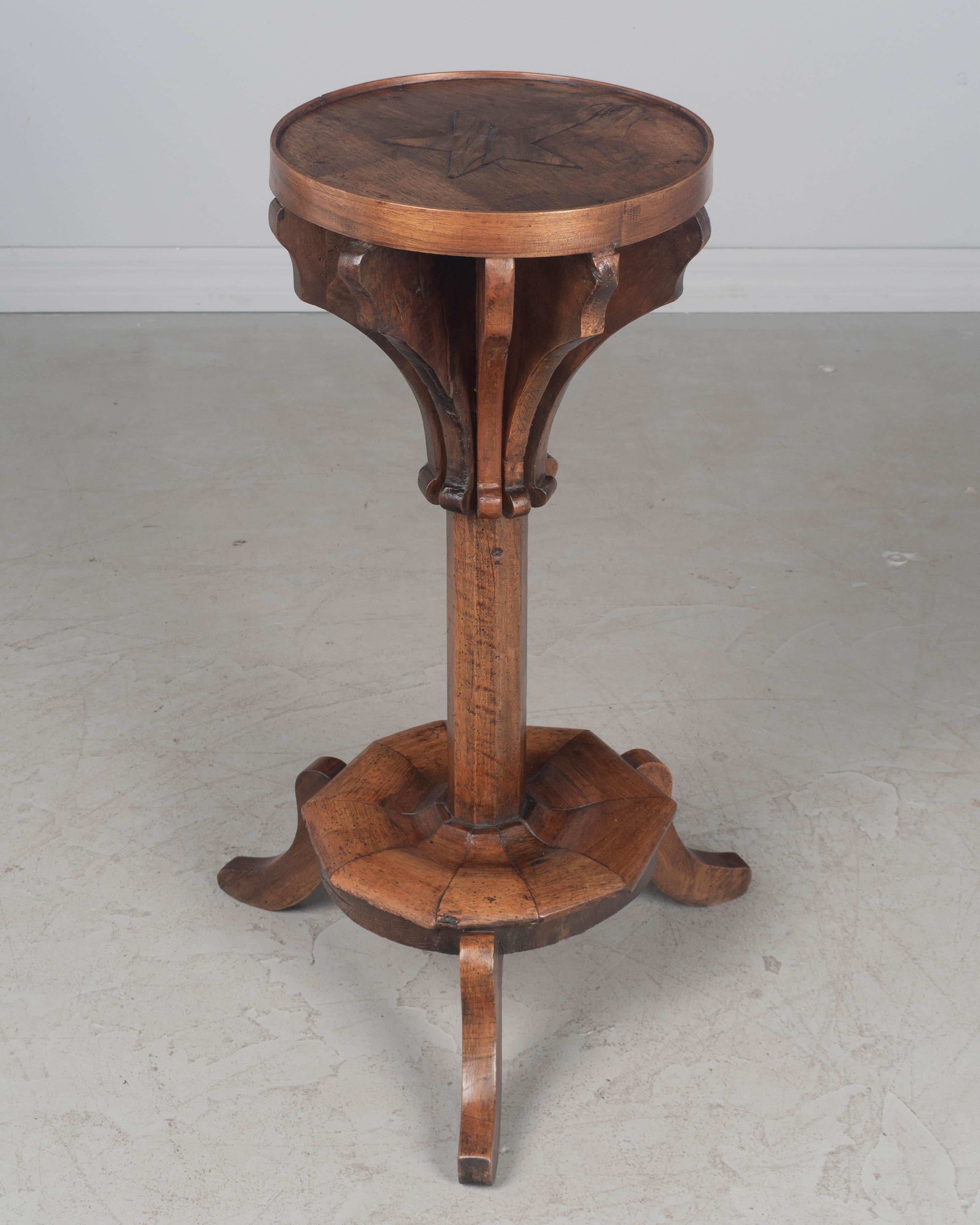 A 19th Century French Art Populaire, or Folk Art, circular side table made of solid walnut. Top has an inlaid five point star. Sturdy pedestal base with tripod legs. Interesting form. Perfect for use as a small drinks table. Circa