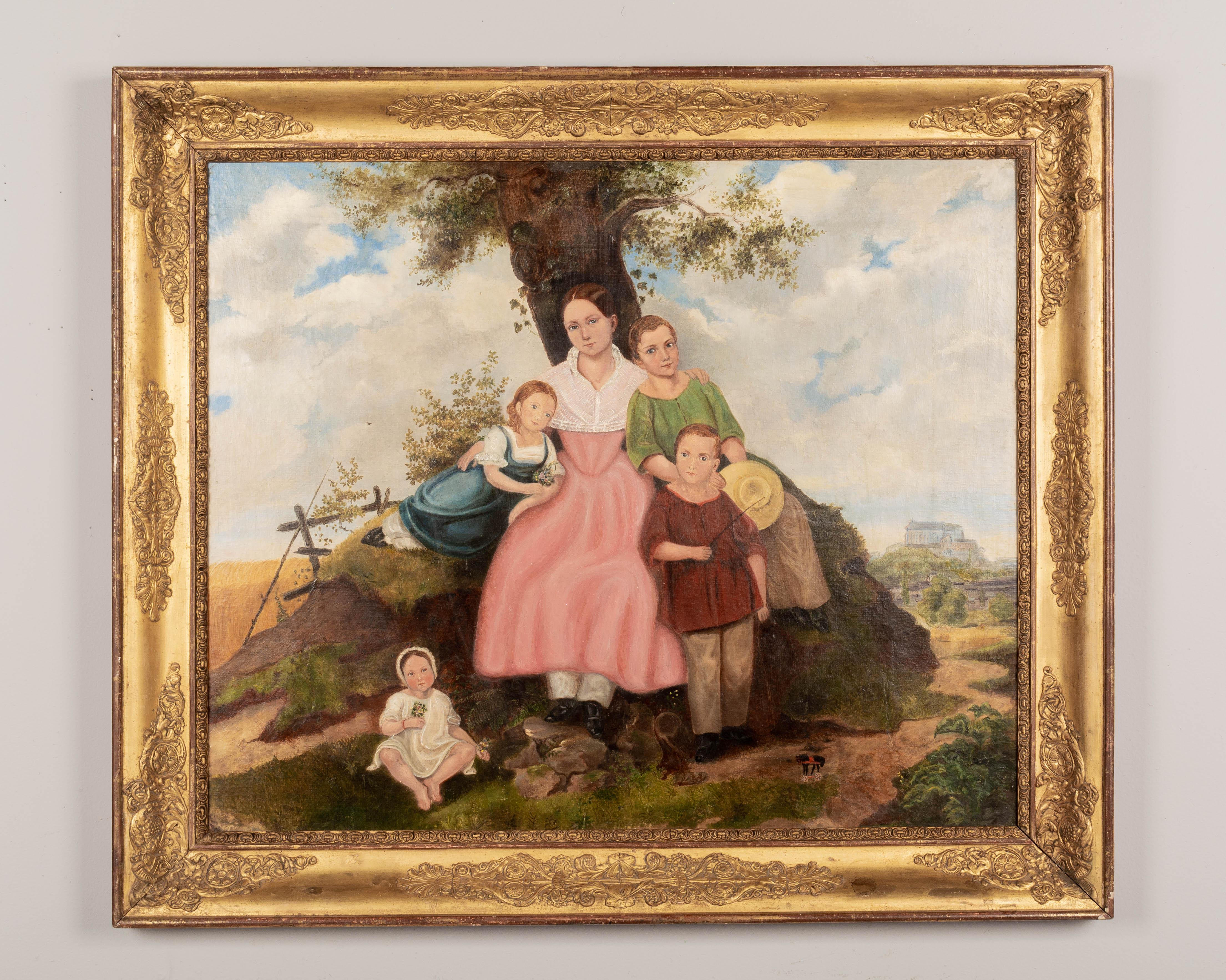 A 19th century French folk art family portrait of a mother and her four children sitting beneath a tree in a pastoral setting. Oil on board. Unsigned. Giltwood frame with gesso decoration.