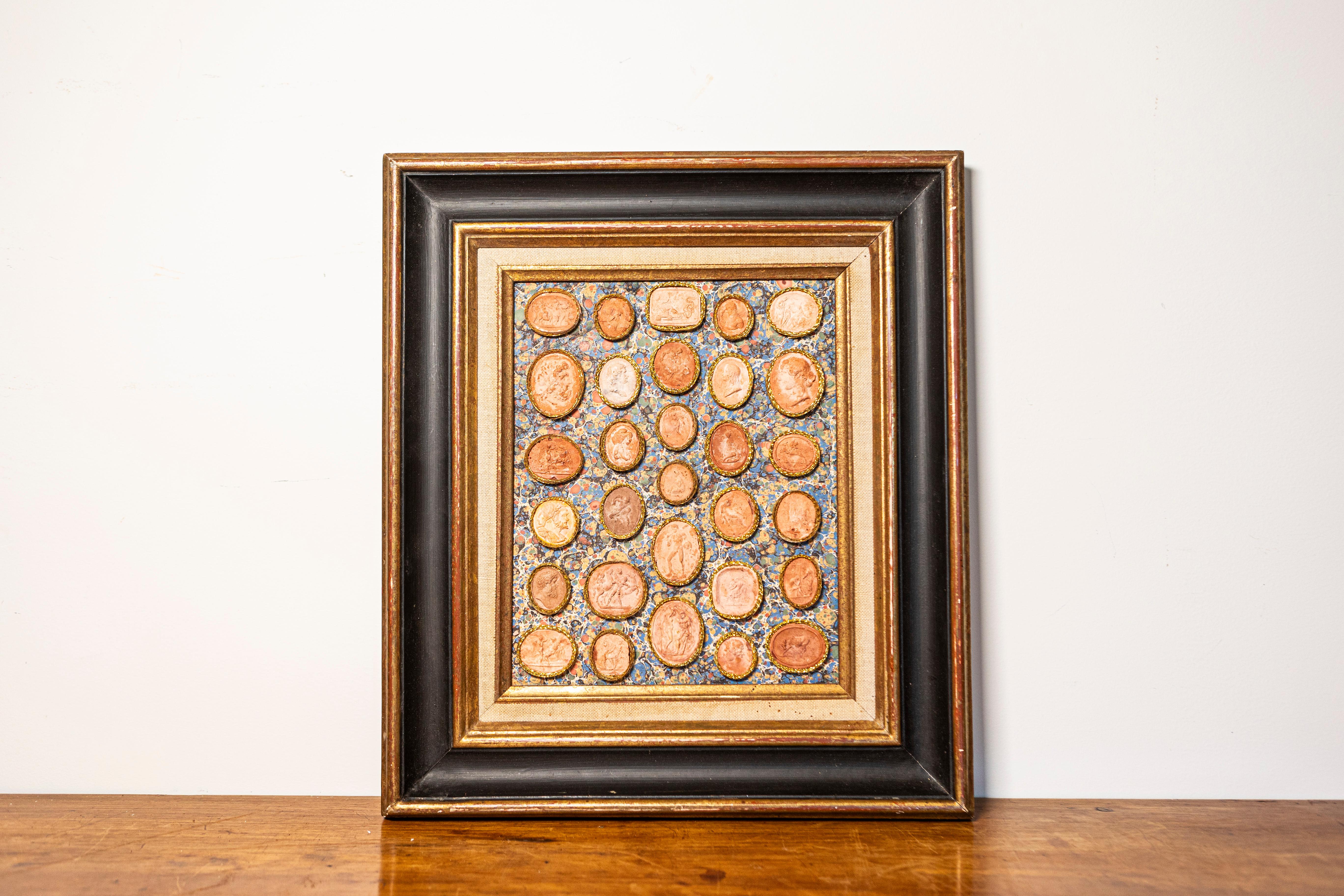 This exquisite 19th-century French framed collection of cameos presents a stunning display of classical artistry. The composition features an array of intricately detailed terracotta-hued cameos, each carefully set within an ornate gilt frame. These