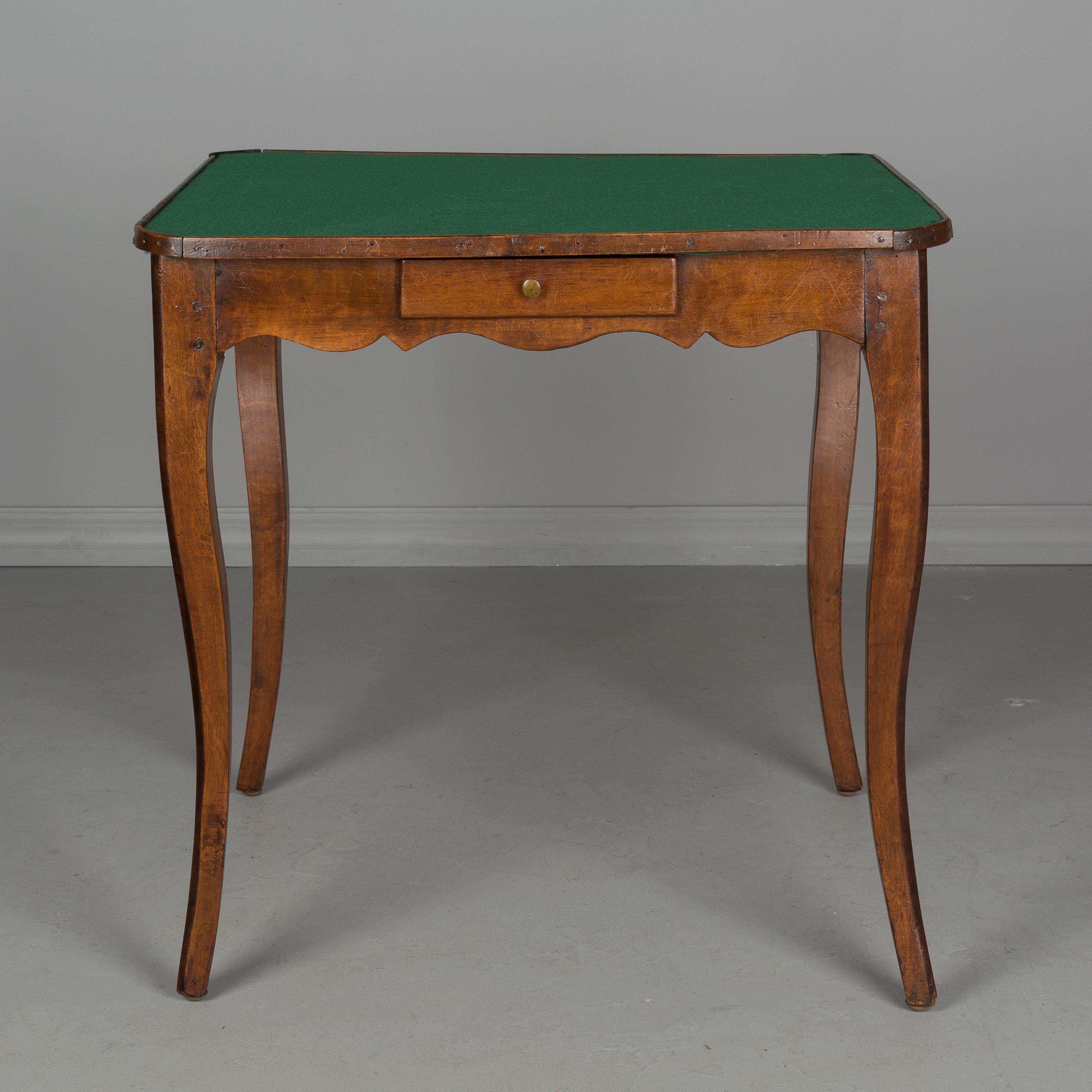 An early 19th century French Louis XV style game table made of walnut with pegged construction, curved legs and four drawers with brass knobs. New felt top. Some replaced corner trim. Please refer to photos for more details. We have a large
