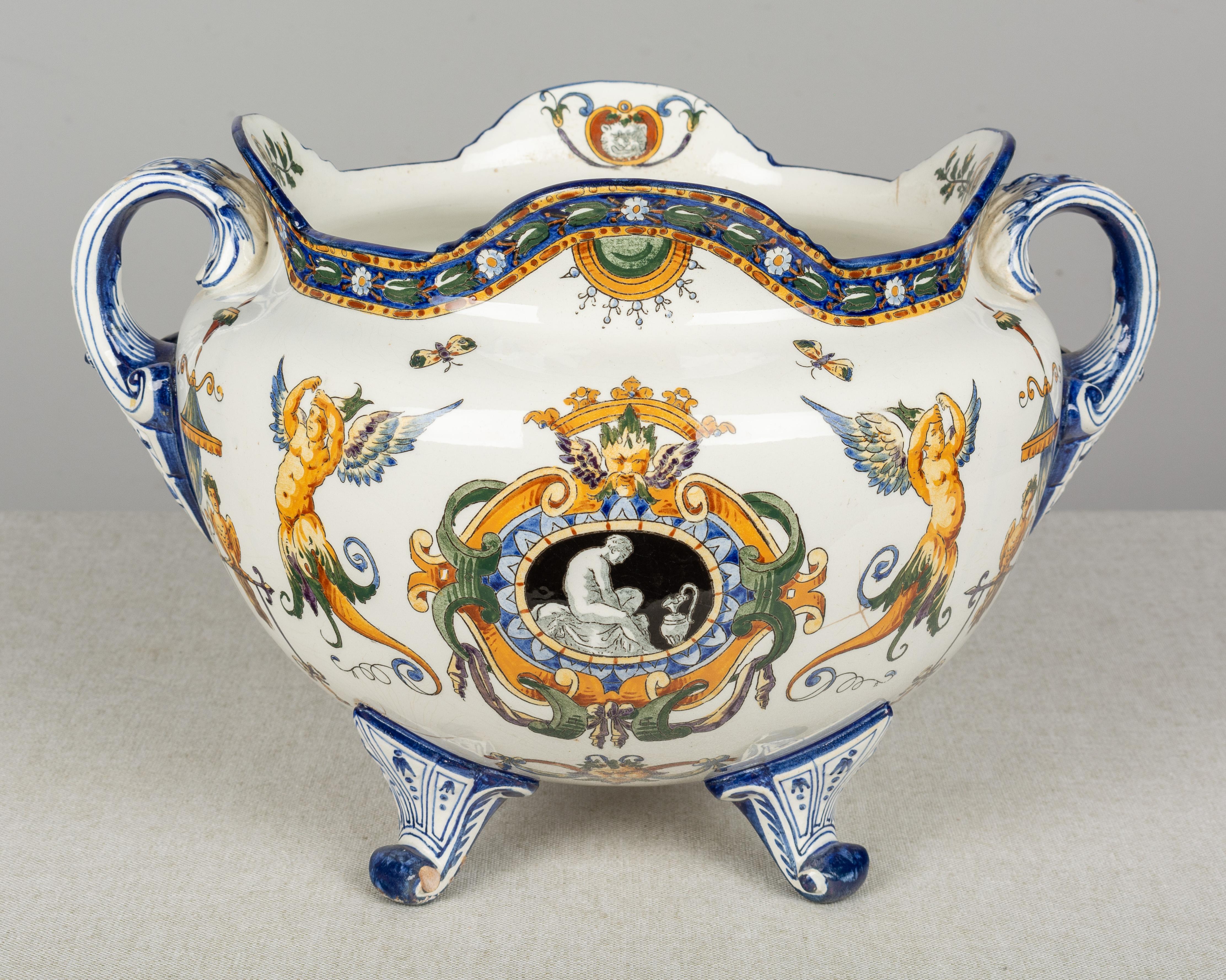 A 19th century French Gien faience cachepot, or planter, with a rounded shape, scalloped rim, two handles and four curved feet. Hand-painted in orange, yellow, green and blue with Renaissance style imagery. Classical central medallion, allegory