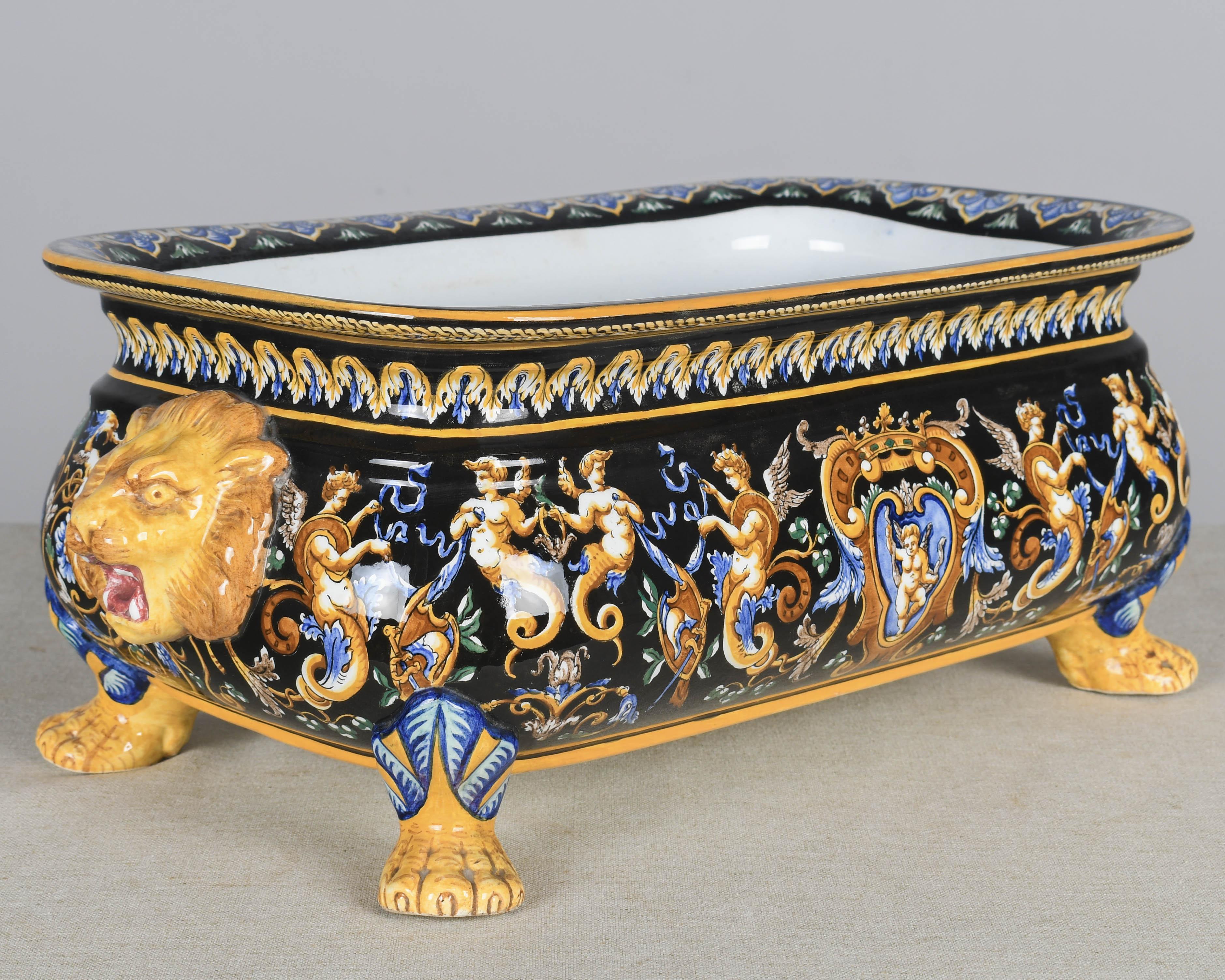 Una jardinière in ceramica faience francese della fine del XIX secolo, o ciotola da centrotavola con piede poco profondo. Immagini in stile rinascimentale dipinte a mano in arancione, giallo, verde e blu su fondo nero con manici scultorei a testa di