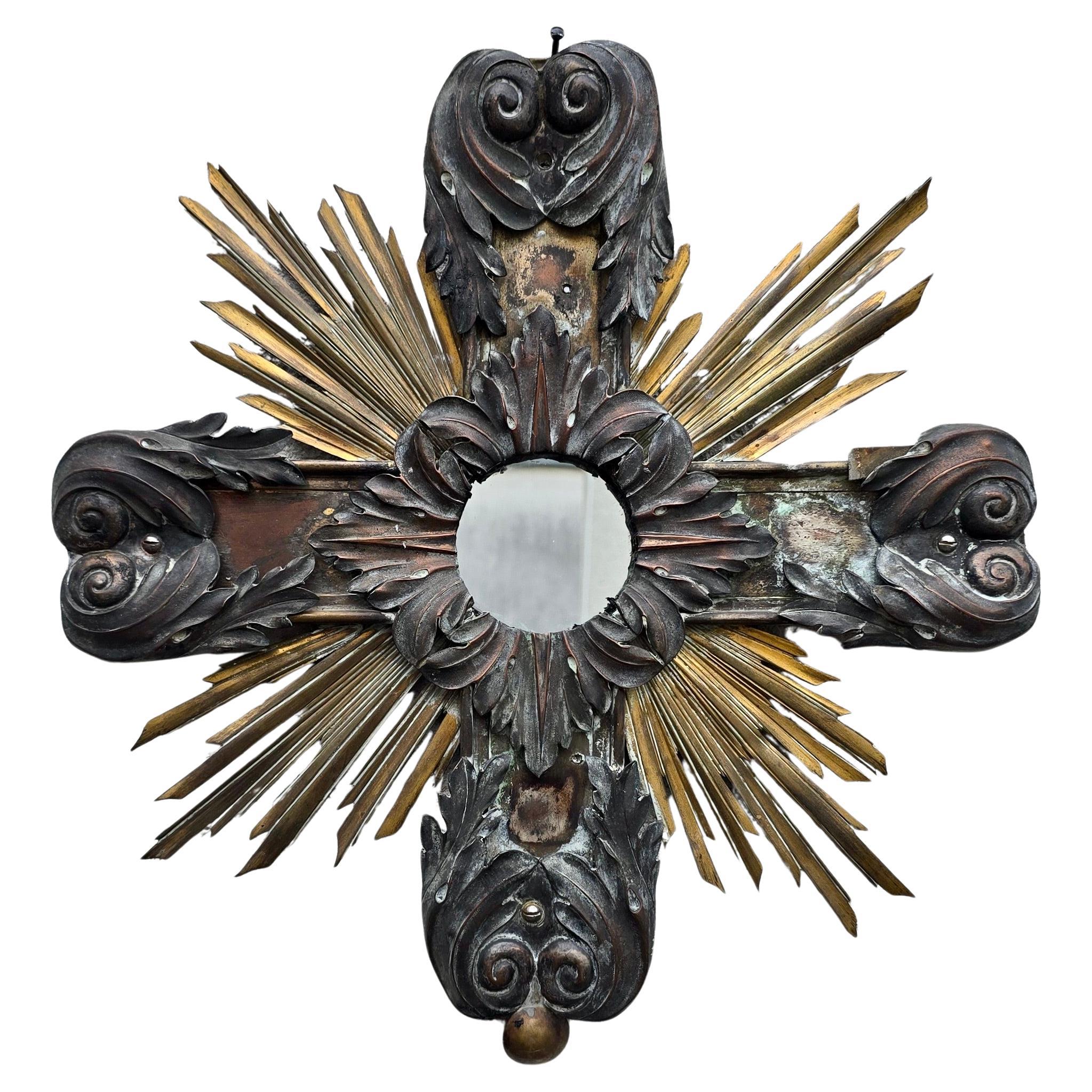 A rare 19th-century French ecclesiastical wall mirror in the form of a radiant cross, handcrafted from gilded and patinated copper and brass. The circular mirror is framed by sculpted scrolls and golden rays, combining Baroque elegance with