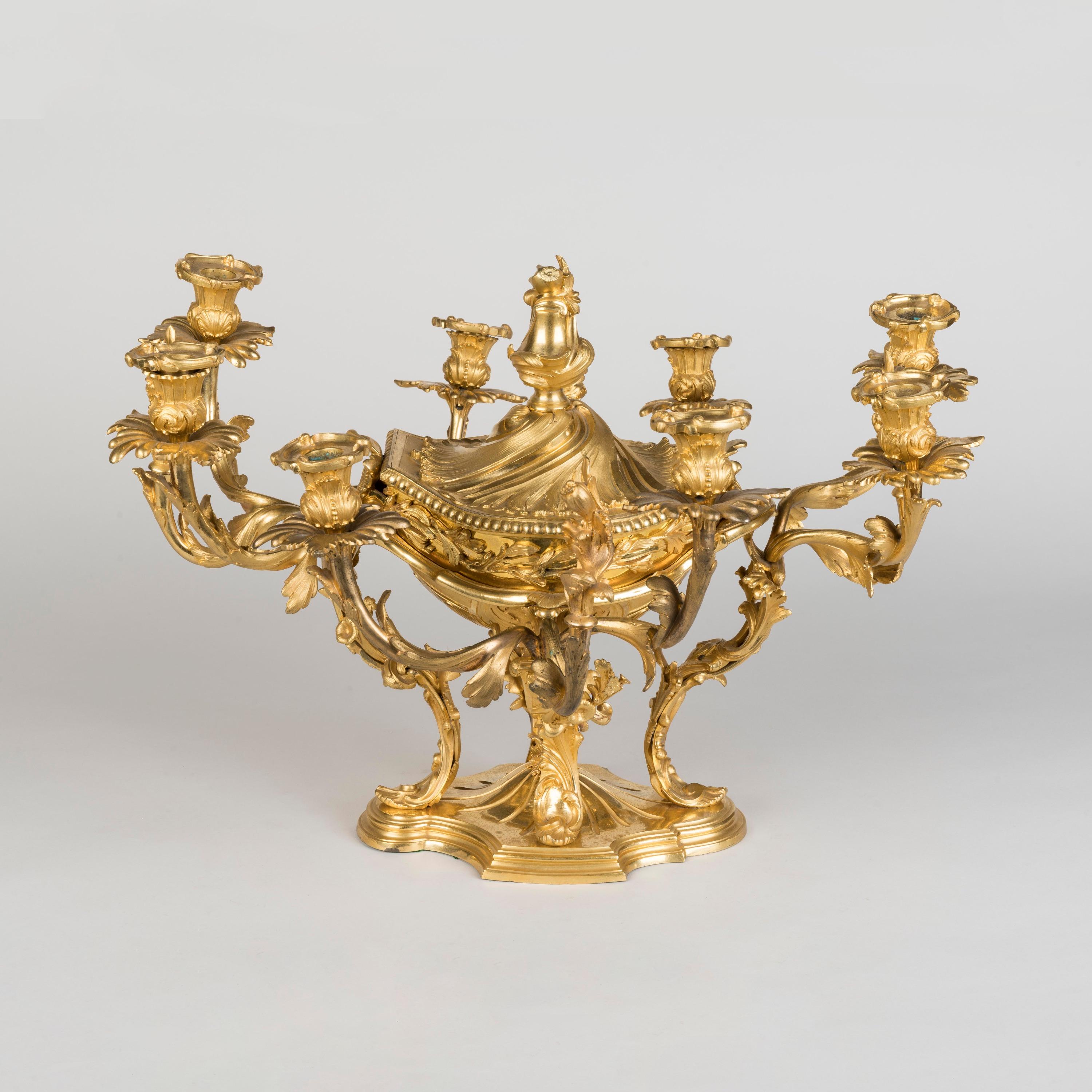 An Ormolu centrepiece in the Rococo Manner

Constructed in gilt bronze of refined casting and finished with burnished surfacing, rising from a shaped and moulded plinth, with four acanthus scrolled legs supporting the central lidded bowl, issuing