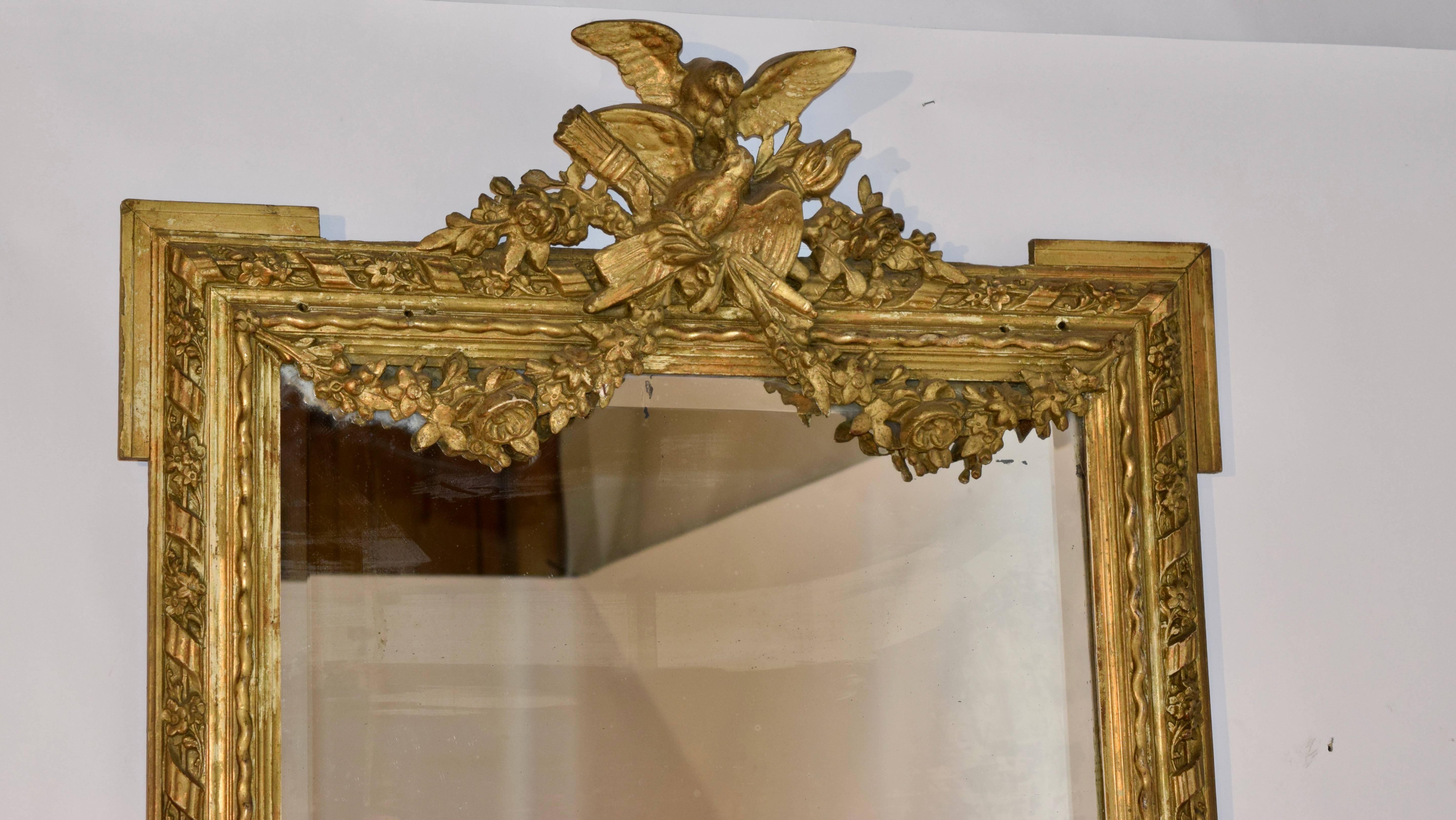 19th century large wall mirror from France. Gorgeous frame with ribbons and flowers, ending in a wonderful floral swag at the top with two birds. Small holes in top of frame where it used to be mounted to a wall.  Original mercury glass mirror has