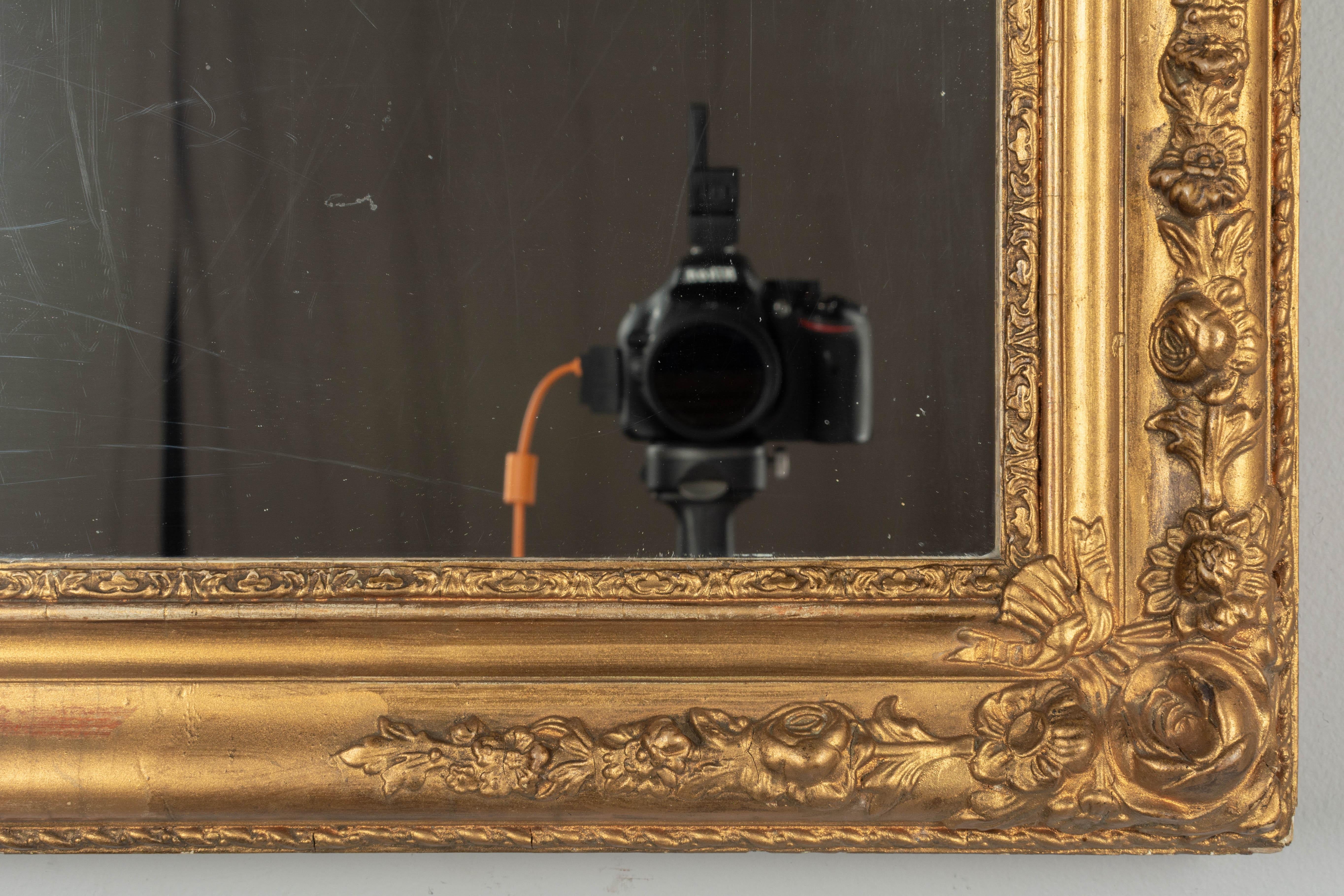 A small 19th century French gilded mirror with carved floral corner decorations. Pine frame with gilded gesso. Original mirror with old silvering and light scratches. May be hung vertically or horizontally. Please refer to photos for more details.