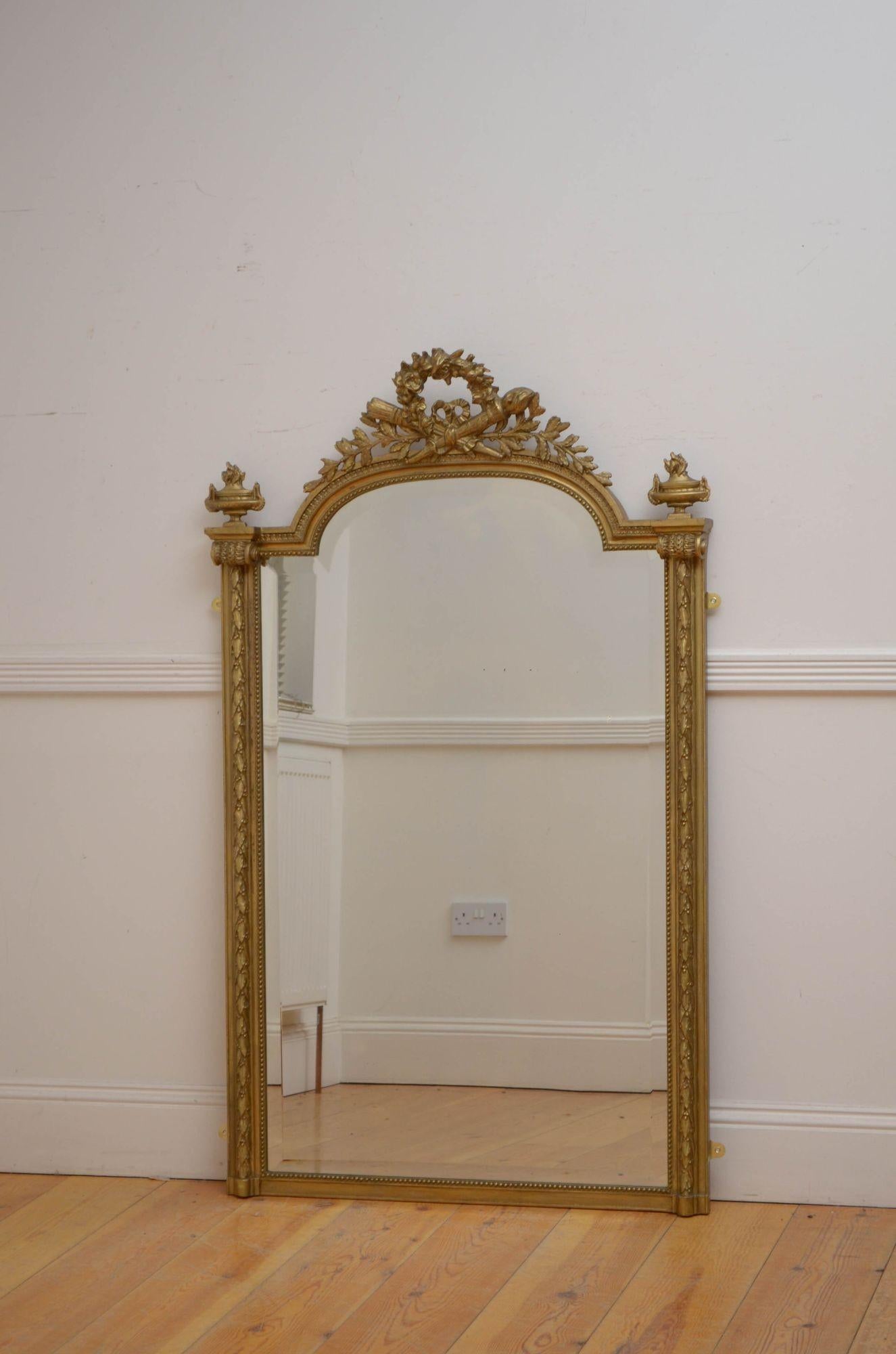 Sn5391 fine 19th century French giltwood wall mirror of slim proportions, having original bevelled edge glass with minor imperfections in gilded frame with laurel leaf carving, beaded edge and leaf decorated crest flanked by two urns. This antique
